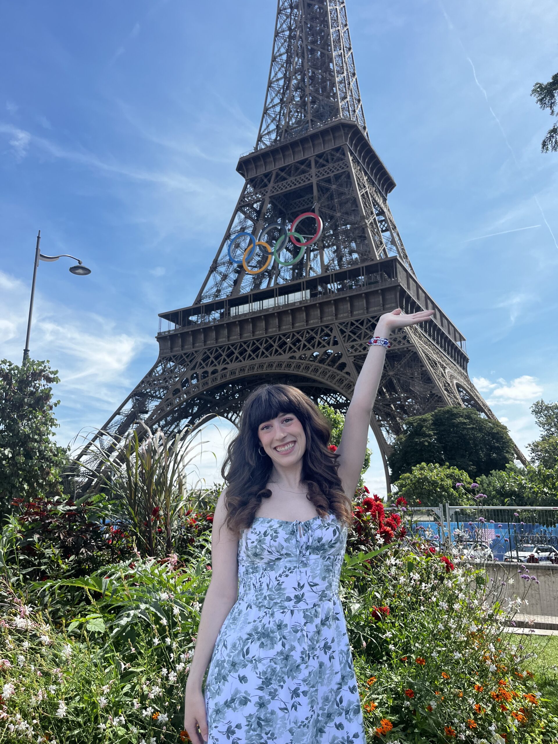 Bella posing in front of the Eiffel Tower in summer 2024 when the monument had the Olympics rings on the front of it.