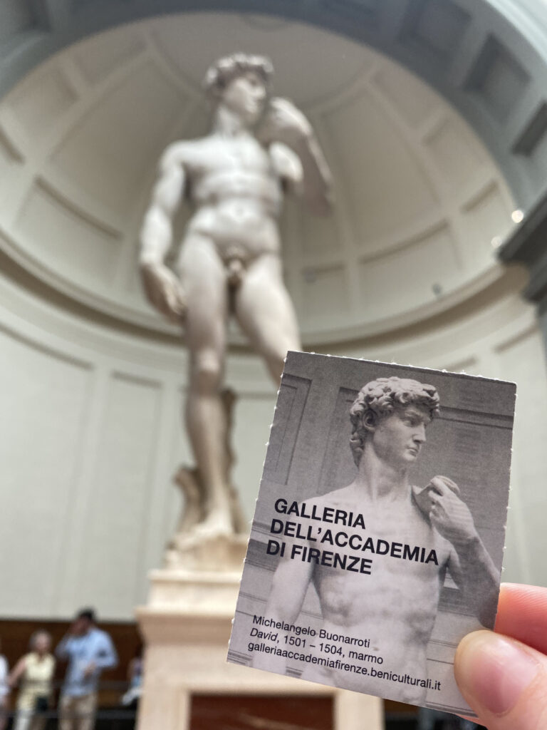 Michelangelo's David sculpture behind a ticket to the famous Galleria dell’Accademia di Firenze.