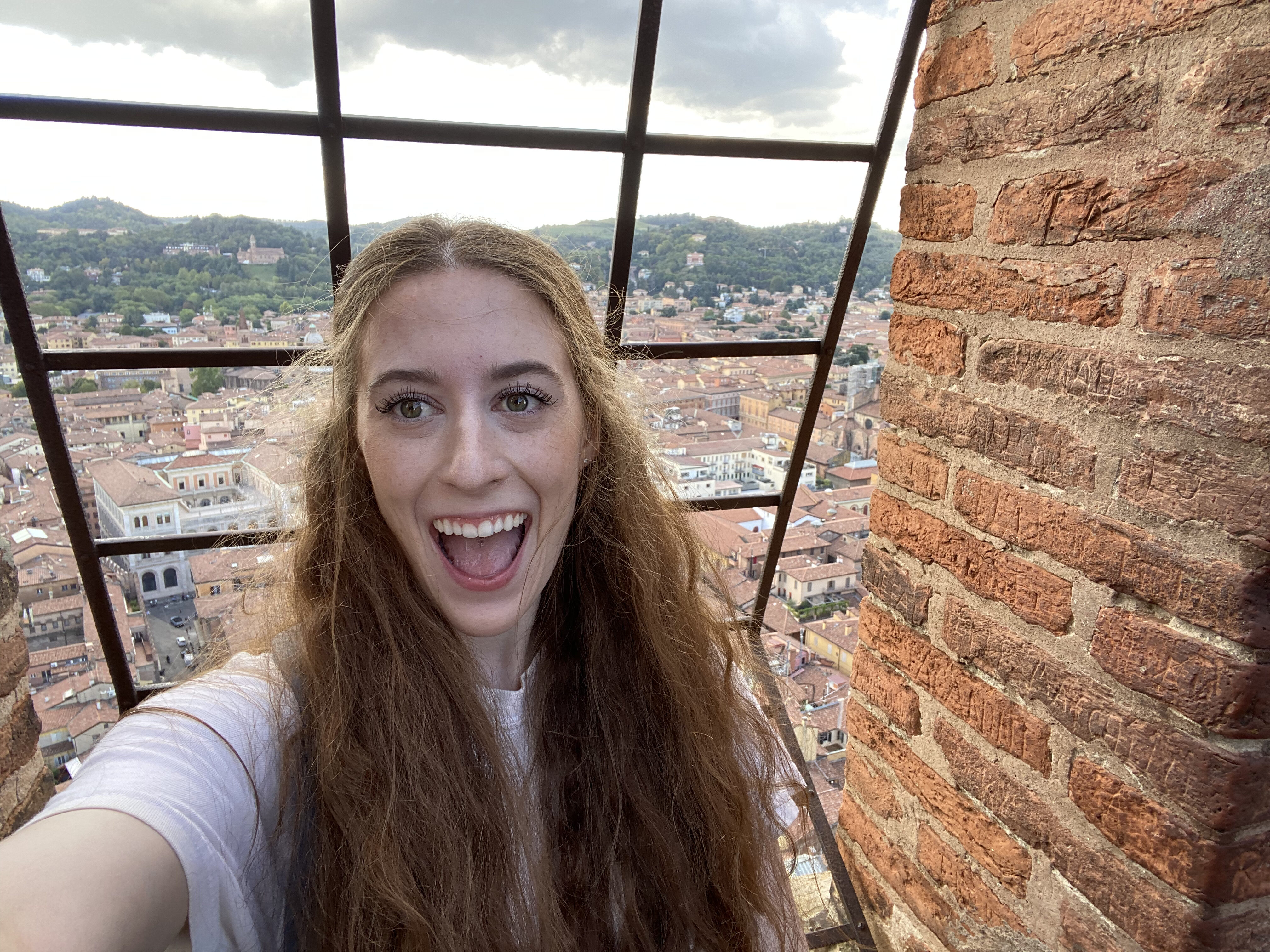 Bella smiles in front of the orange roofs of Bologna at the top of the Asinelli Tower.