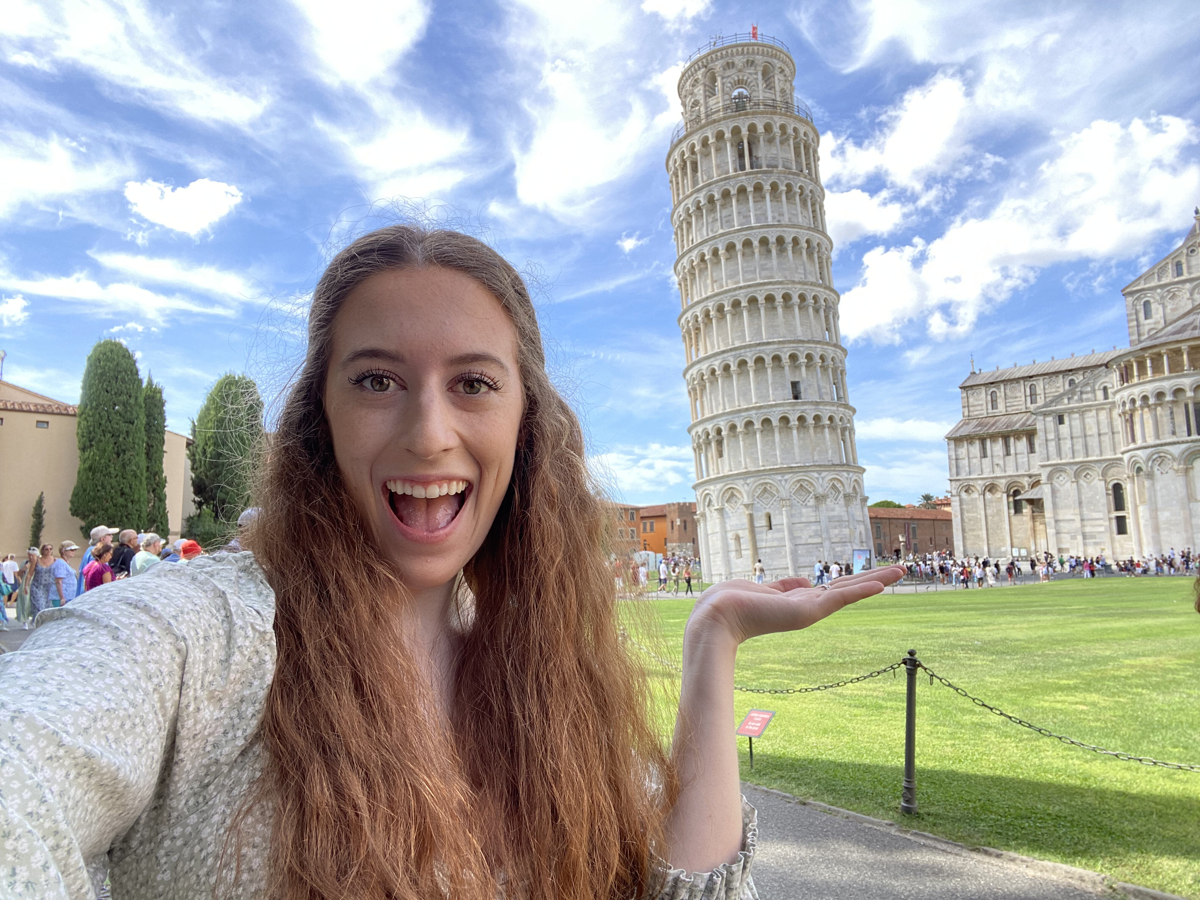 Bella smiles "holding" the Leaning Tower of Pisa.