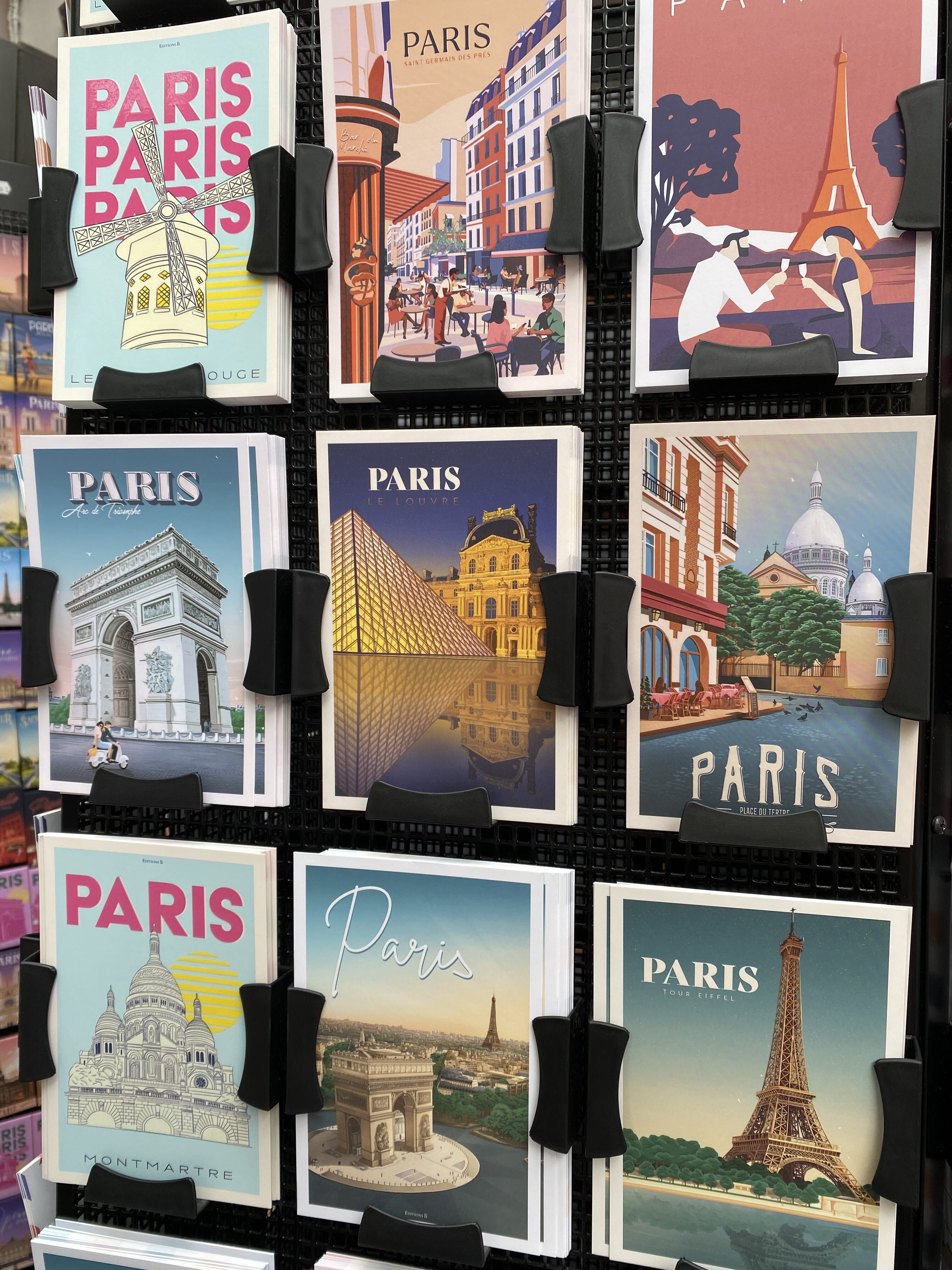 A group of vibrant, colorful Paris postcards with different cartoonish views of landmarks like the Eiffel Tower, the Arc de Triomphe, and the Louvre.