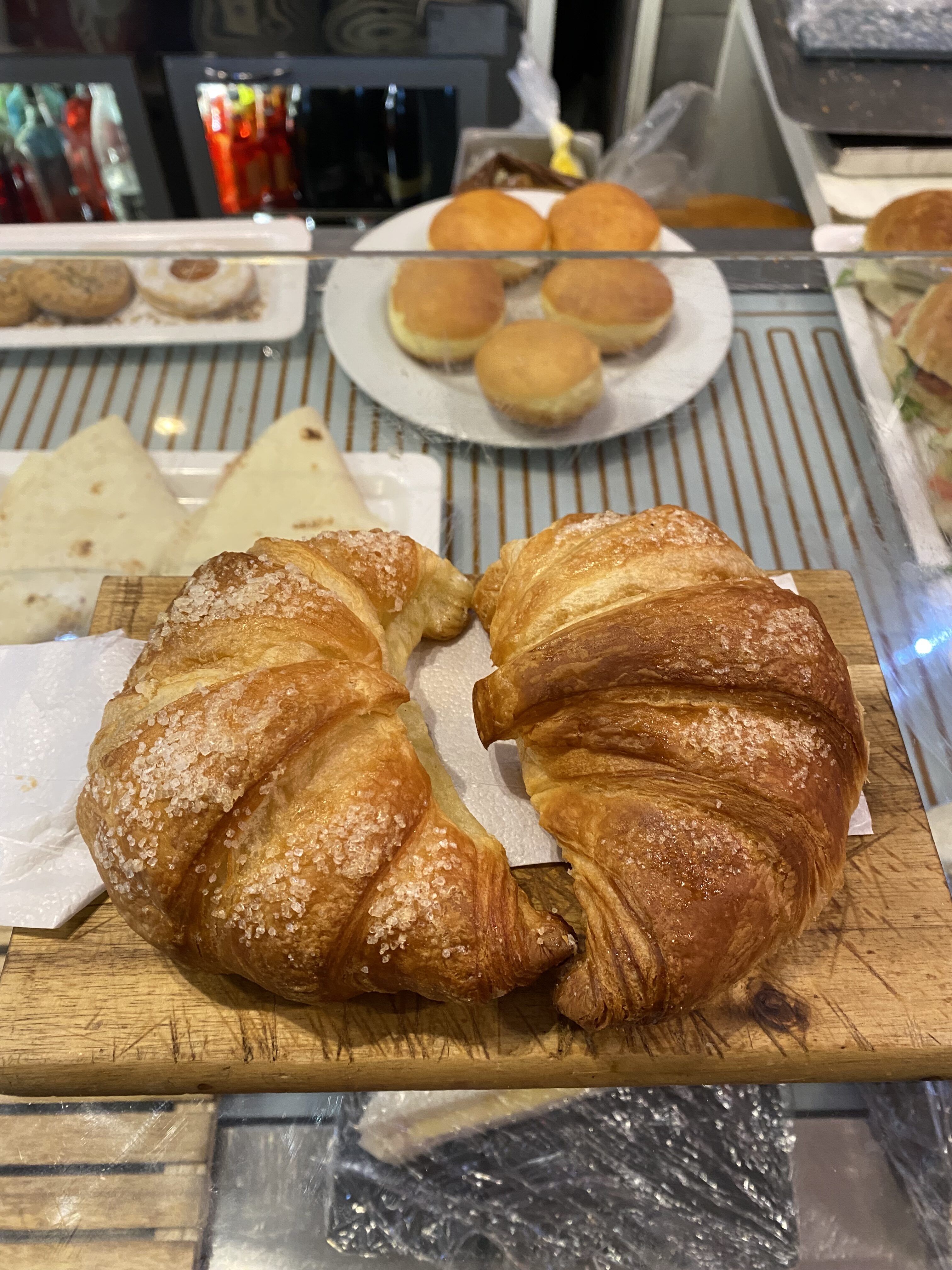 Two delectable, golden Italian croissants joined together on a wooden board.