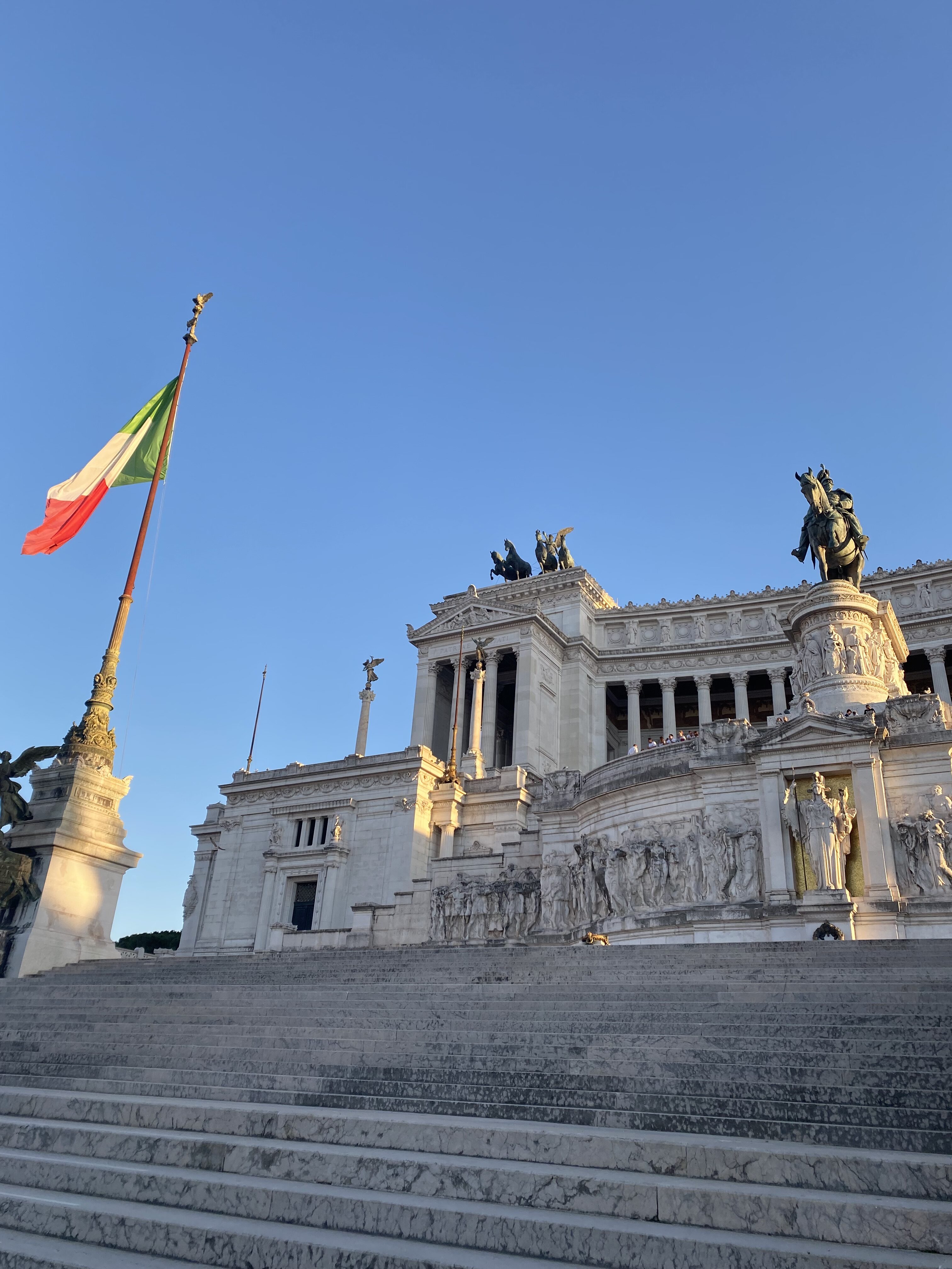 The monumental Vittoriano –pictured with an Italian flag against a bright blue, cloudless sky.