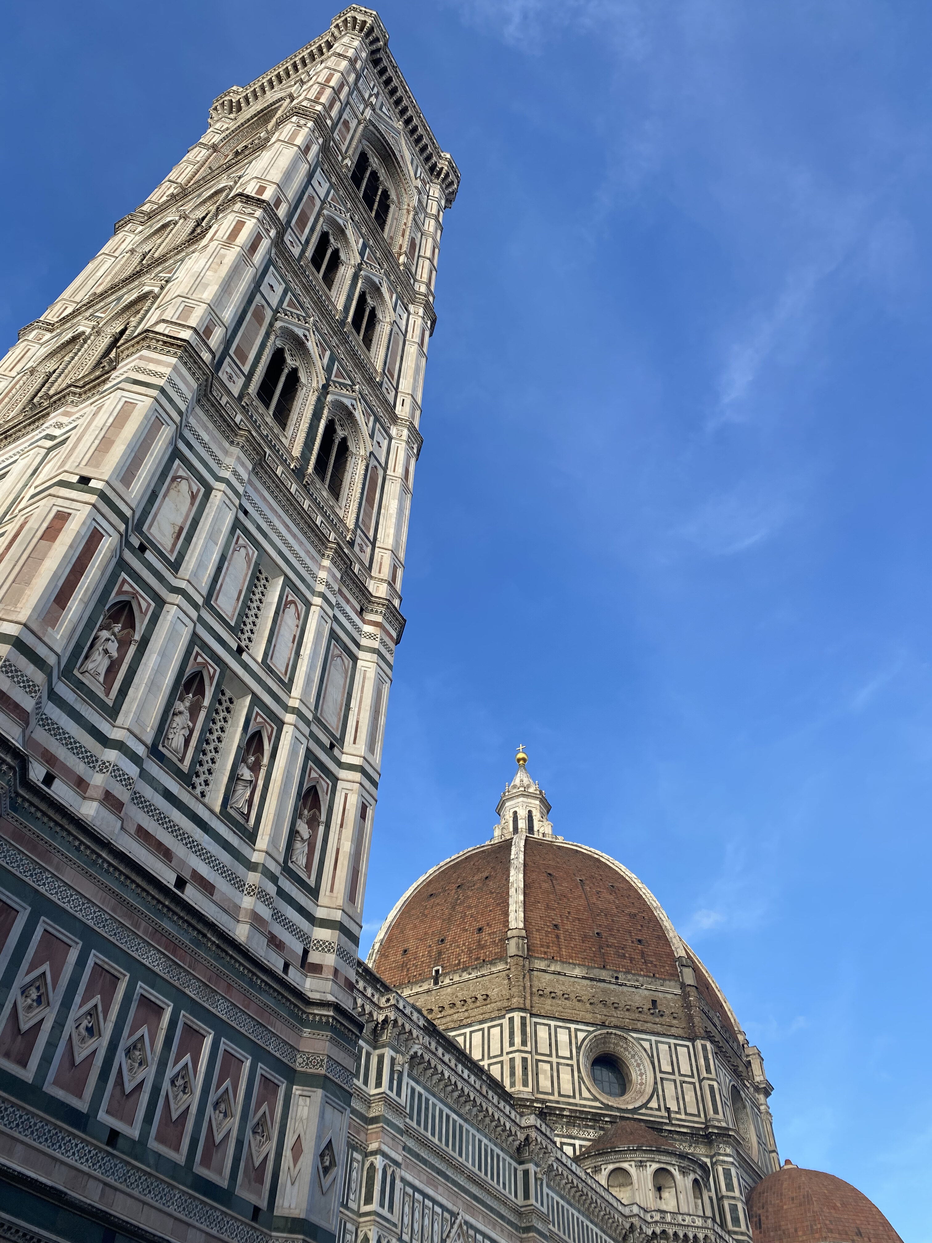 Giotto's Campanile and the famous orange dome built by Brunelleschi. A blue sky frames the monumental structure.