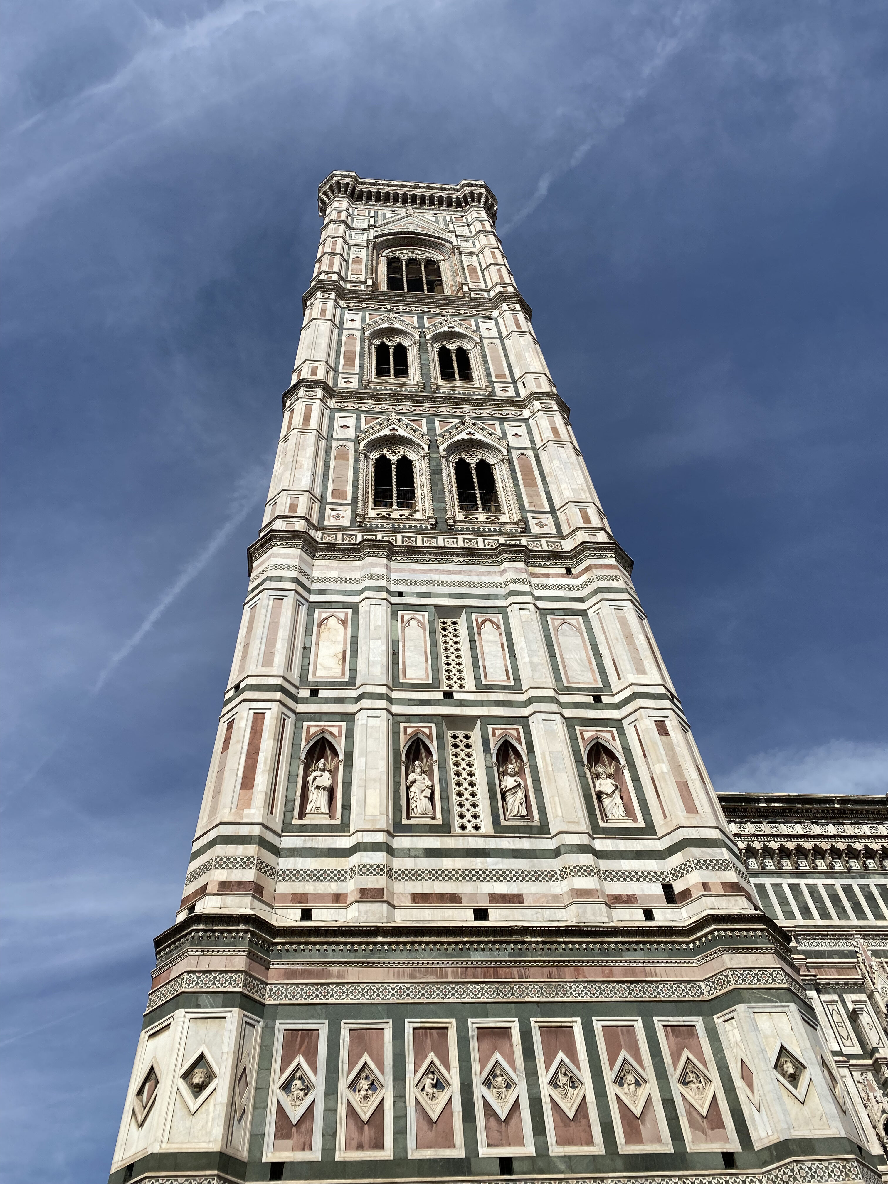 A view of Giotto's Campanile, a magnificent decorative tower in Florence, set against a bright blue sky.