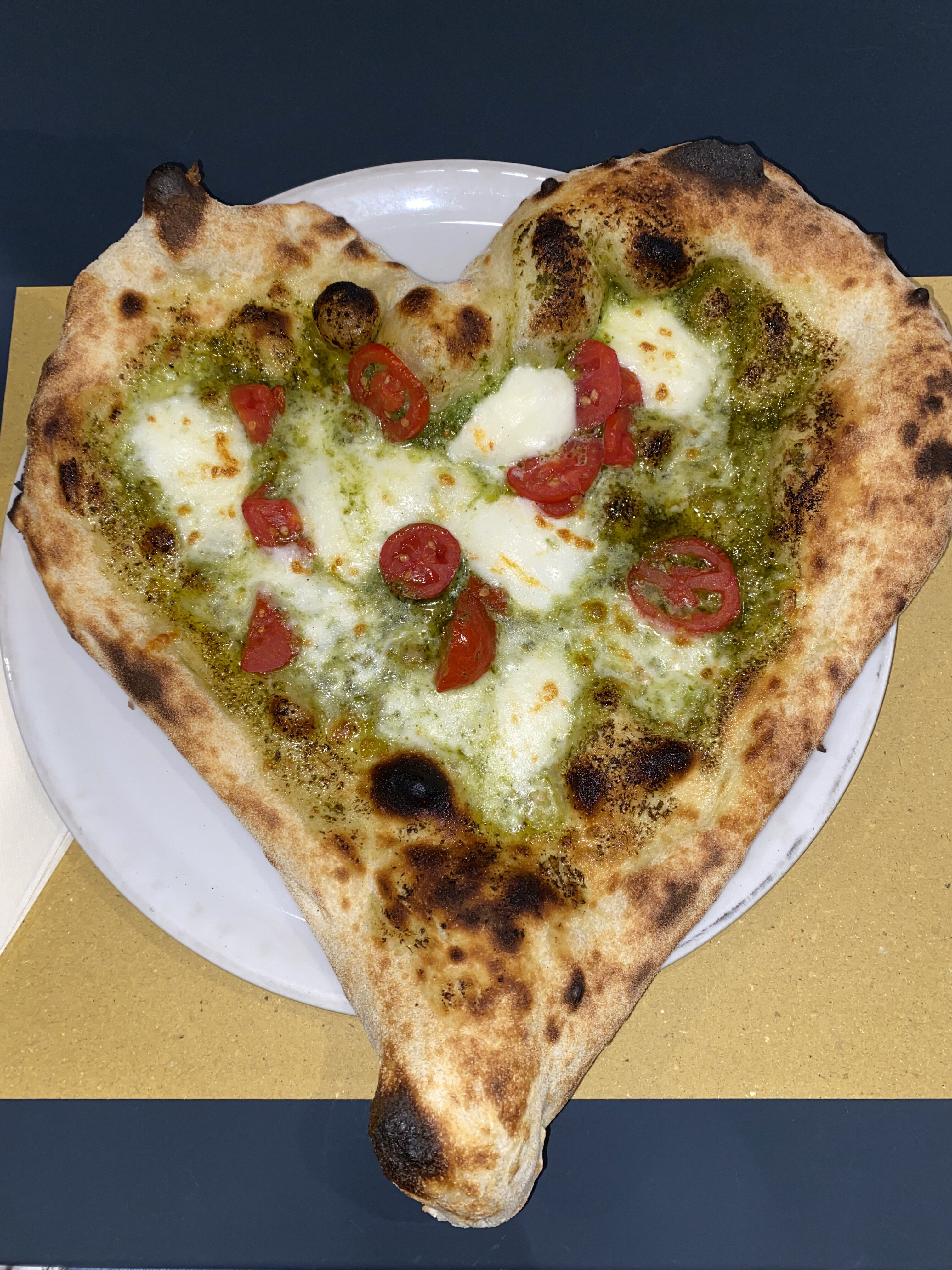 A heart-shaped, Neapolitan-style pizza with halved tomatoes, pesto and mozzarella from Pizza Napoli 1955 in Florence. Part of Beauty and the Bucket Lists, "Where to Eat in Florence" food guide.