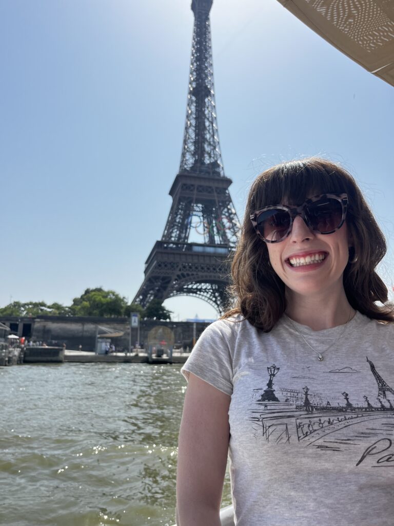 Bella smiling on a Seine river cruise with the Eiffel Tower in the background.