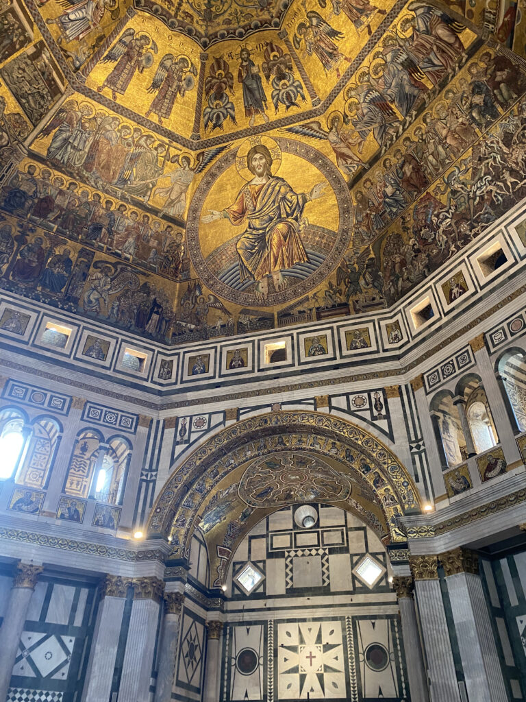 Ornately decorated gold interior of the Baptistery of St. John in Florence, Italy. Elaborate gold mosaics decorate the domed ceiling.