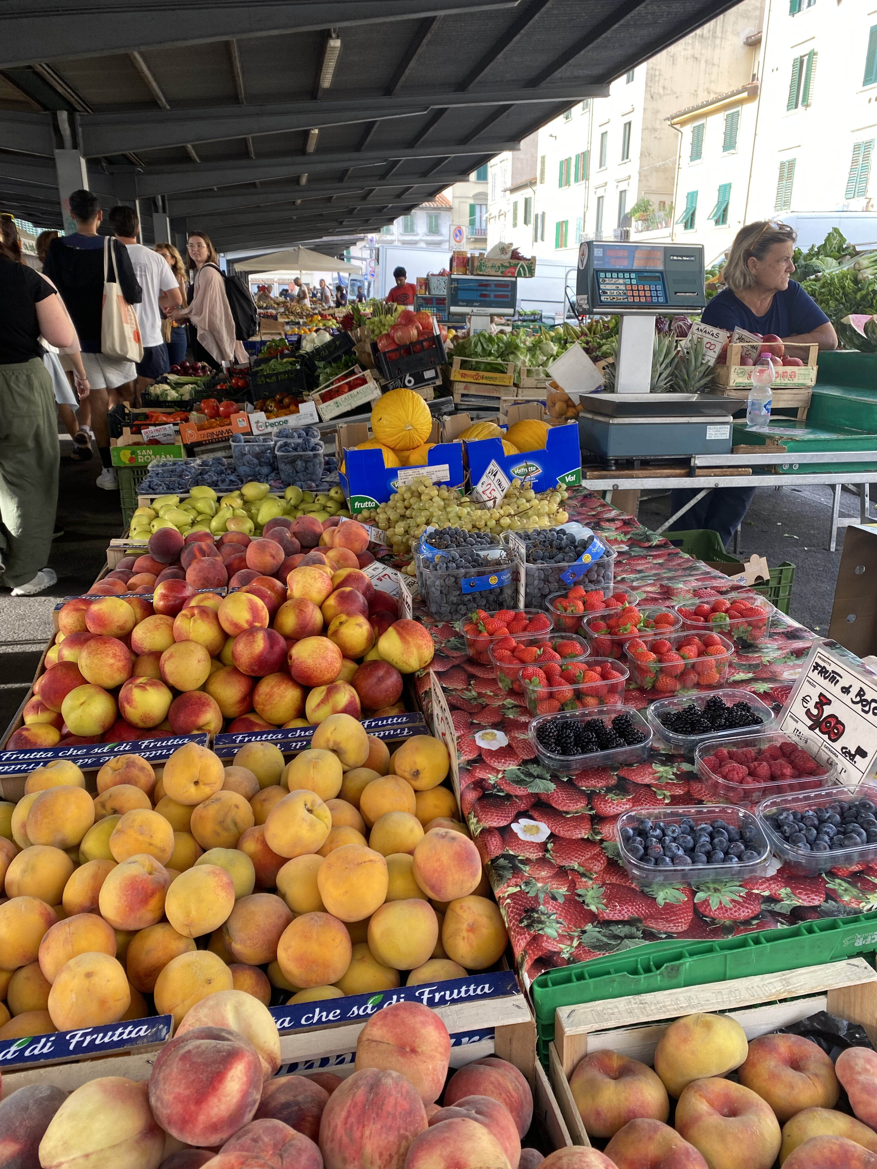 A local market in Florence with colorful fruits like peaches, strawberries and blueberries.