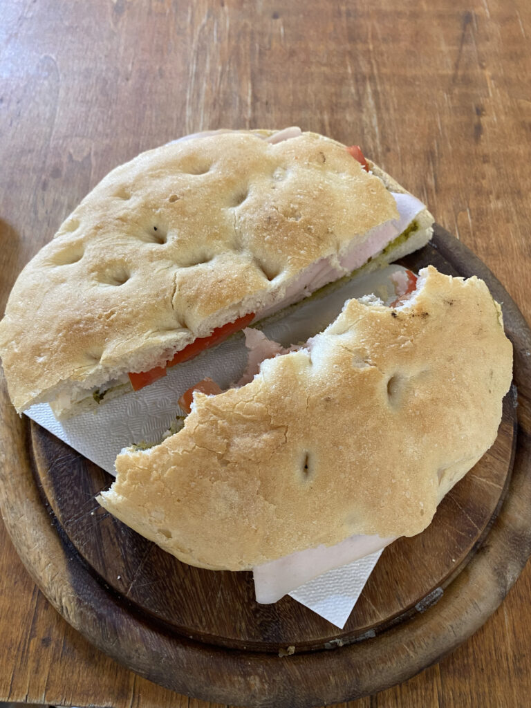 A sandwich on top of a wooden table, with half of it eaten!