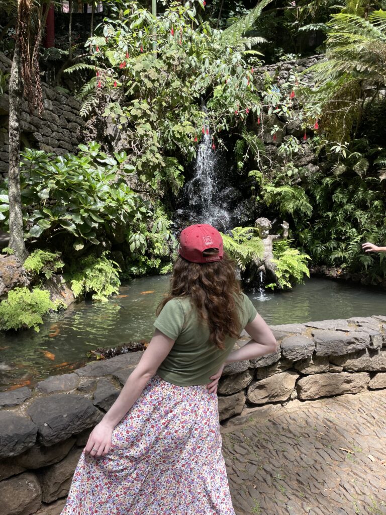 Bella grabbing her skirt, facing towards the green scenery posing at Monte Palace Tropical Garden in Monte (Madeira).