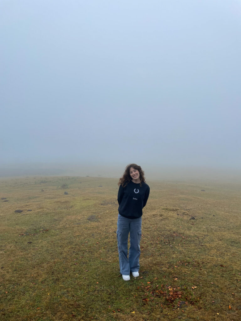 Bella smiling in the Fanal Forest nearly engulfed by fog. Not a single tree is visible in the background due to the thick fog.