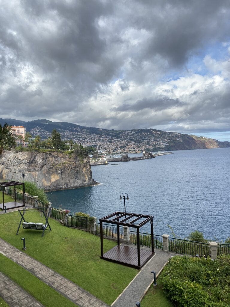 Cliff Bay hotel lawn with a beautiful view of the cliff of São Martinho and the city of Funchal in the distance.