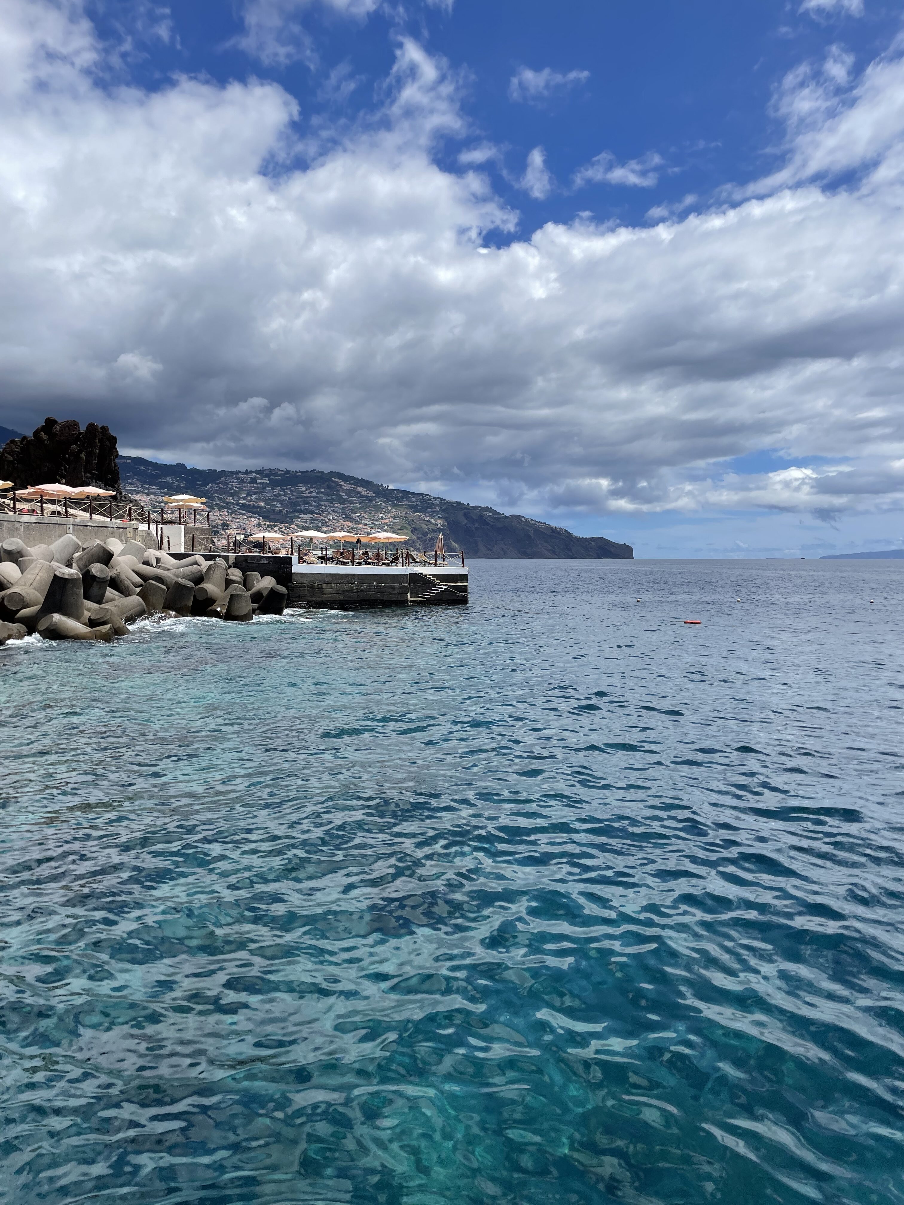 Ocean view with a short dock and the hillside of Madeira in the background.