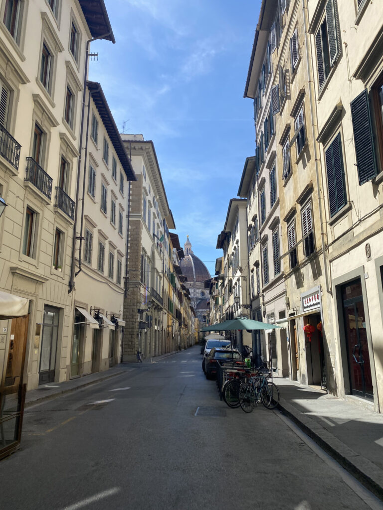 Situated between a row Florentine buildings is the monumental burnt orange Duomo, peeking through the horizon.