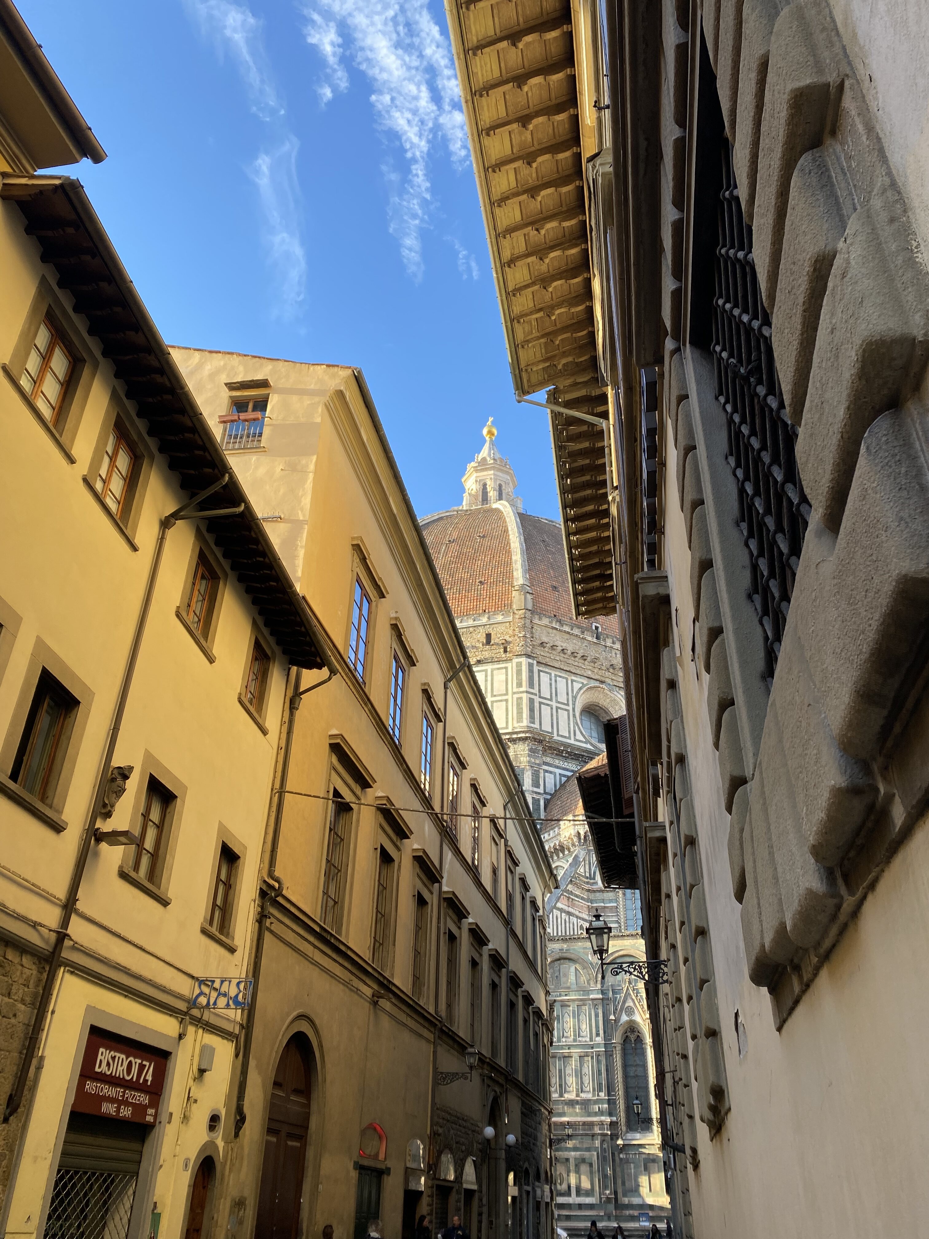 The Duomo in Florence viewed through a narrow alley between two buildings.