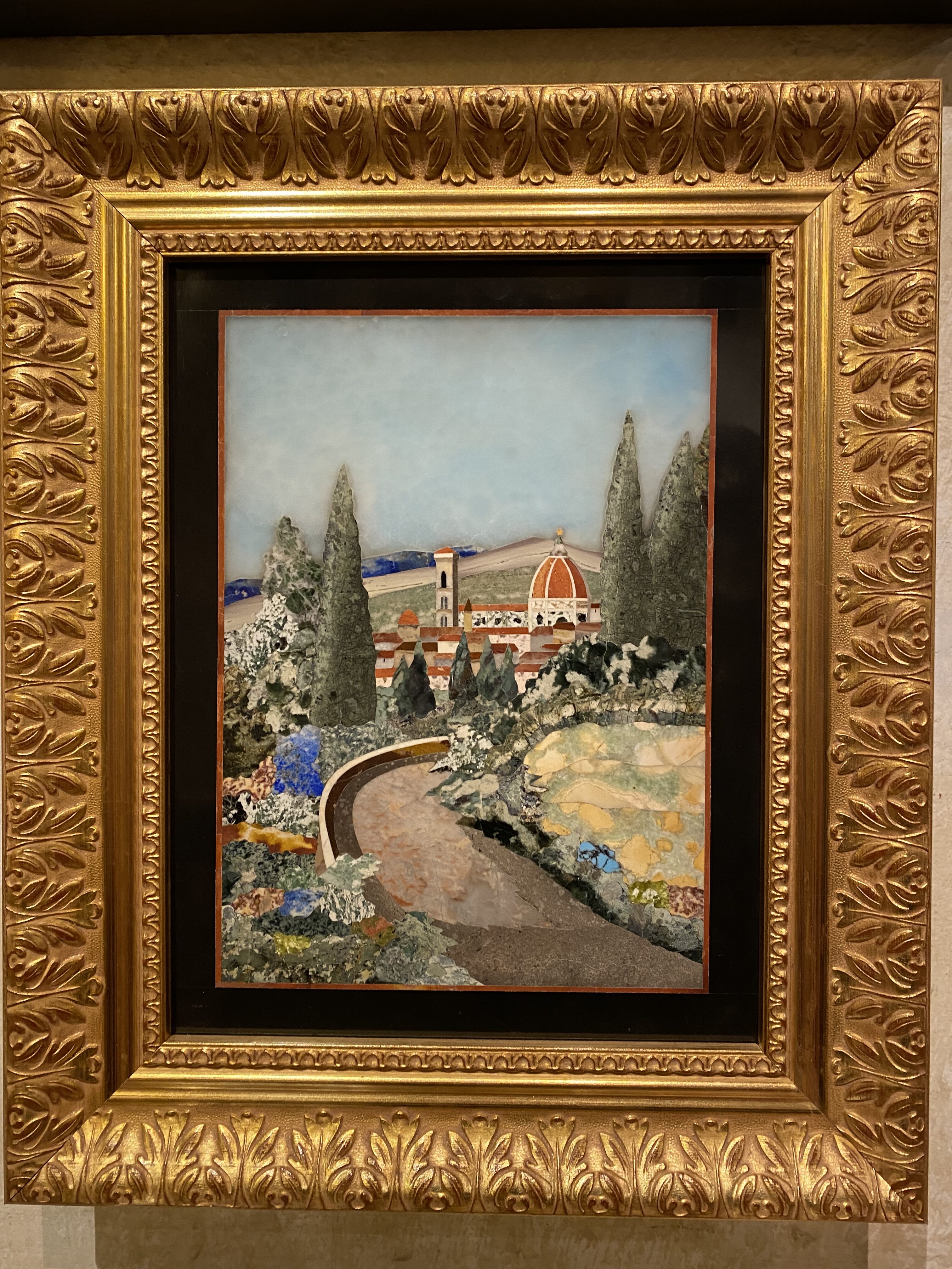 A beautiful Florentine commesso mosaic depicting a stone pathway leading to the Florentine skyline set in an ornate gold frame.