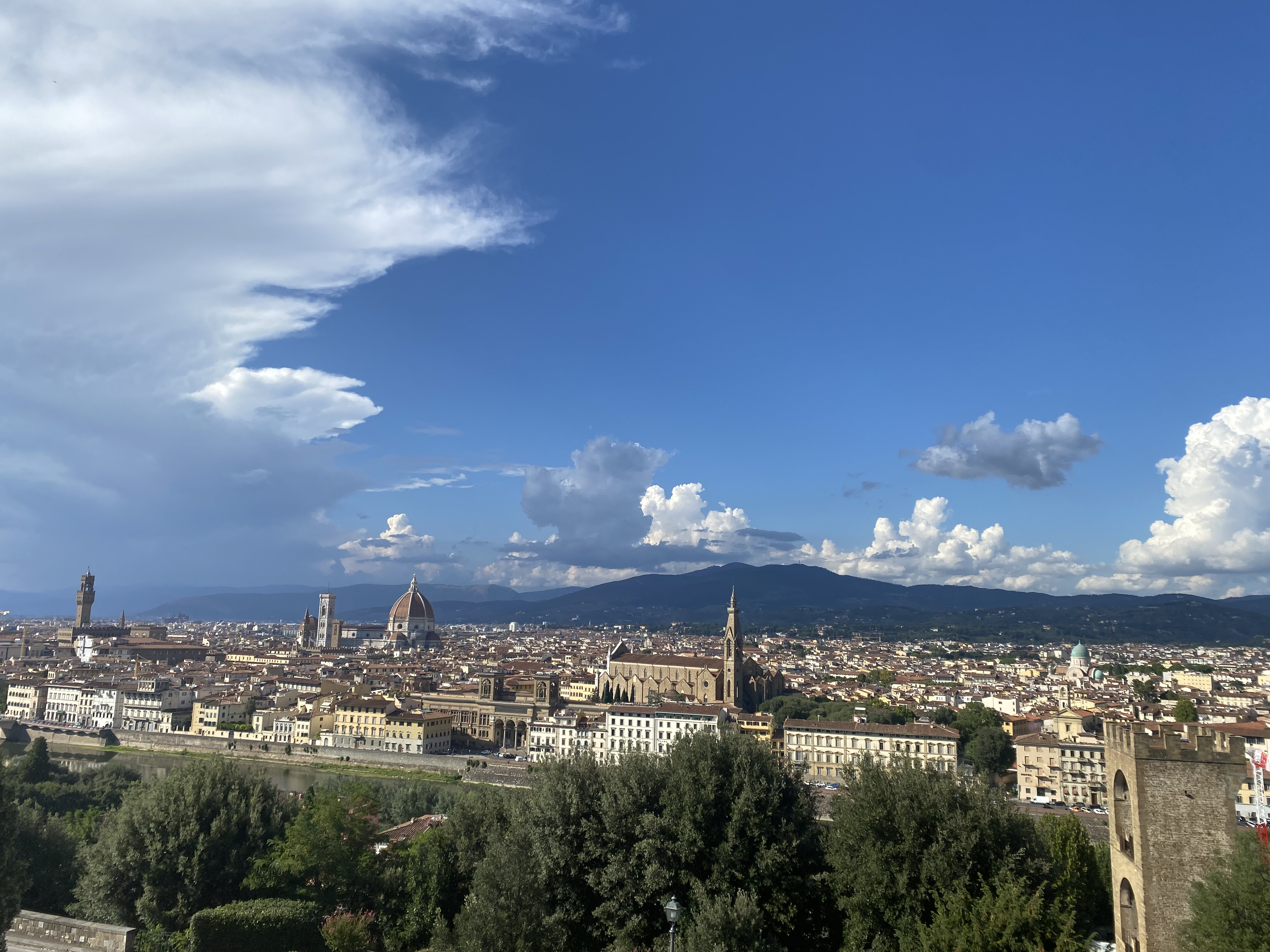 The Florentine skyline, seen from Piazzale Michelangelo, on a bright sunny day with a cloudy blue sky.