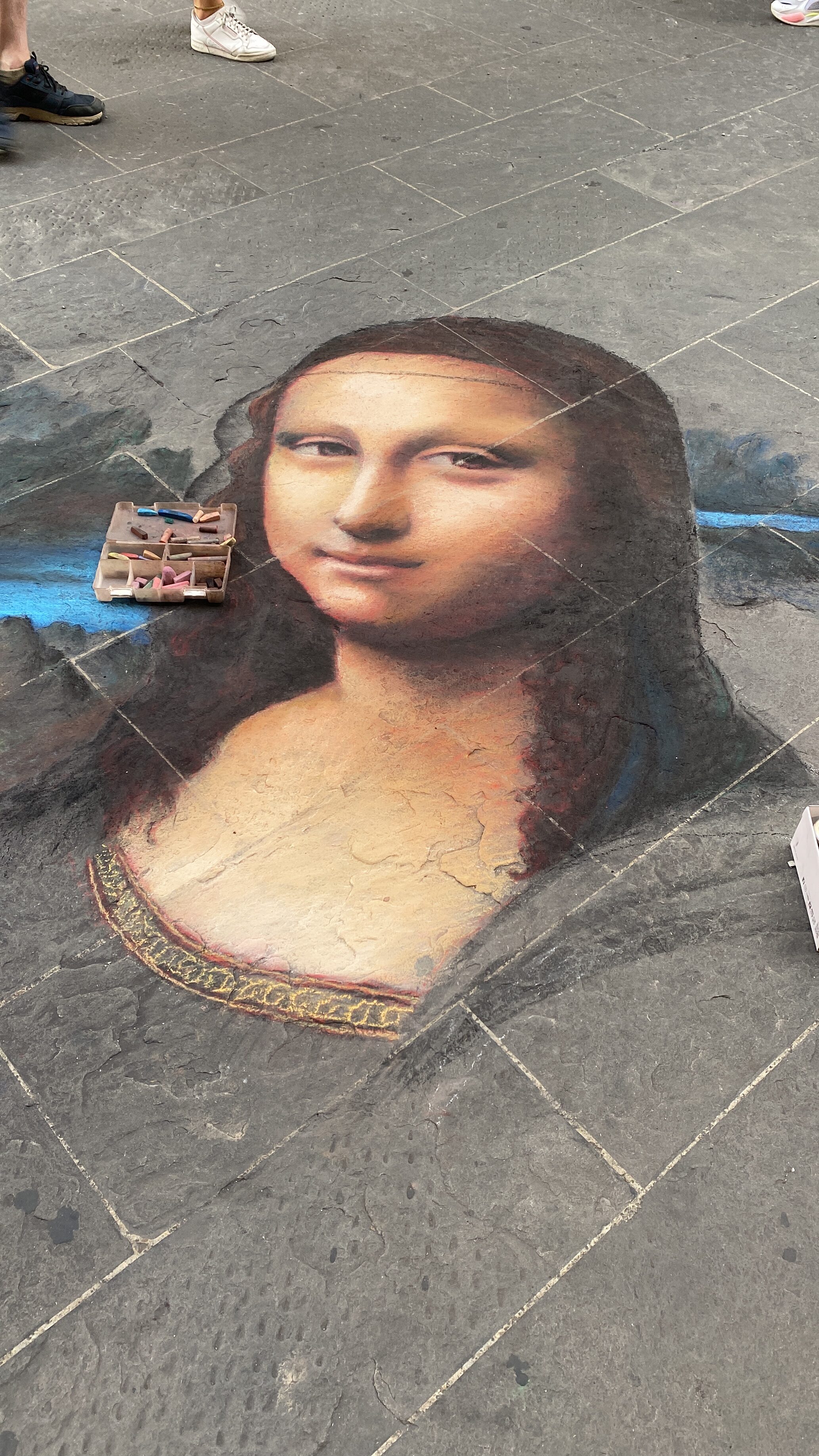A chalk drawing of the Mona Lisa on the cobblestone streets of Florence.