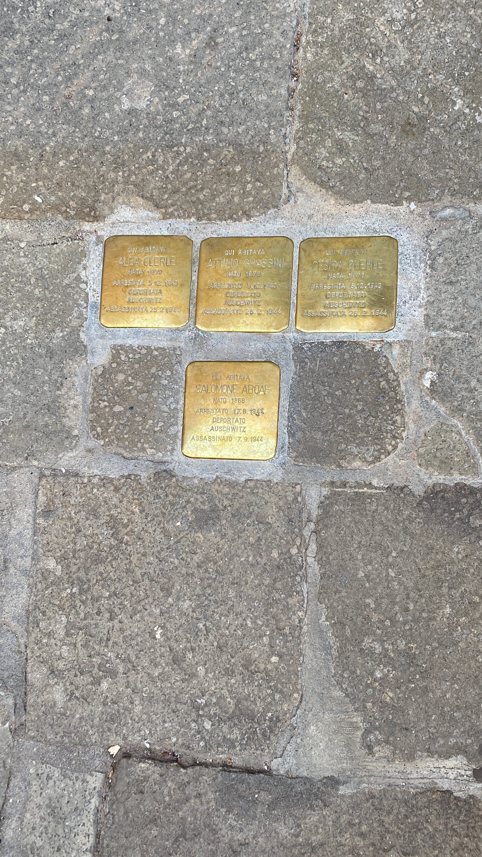 Four gold "stumbling stones" – gold cobblestones set into the weathered cobblestone street.
