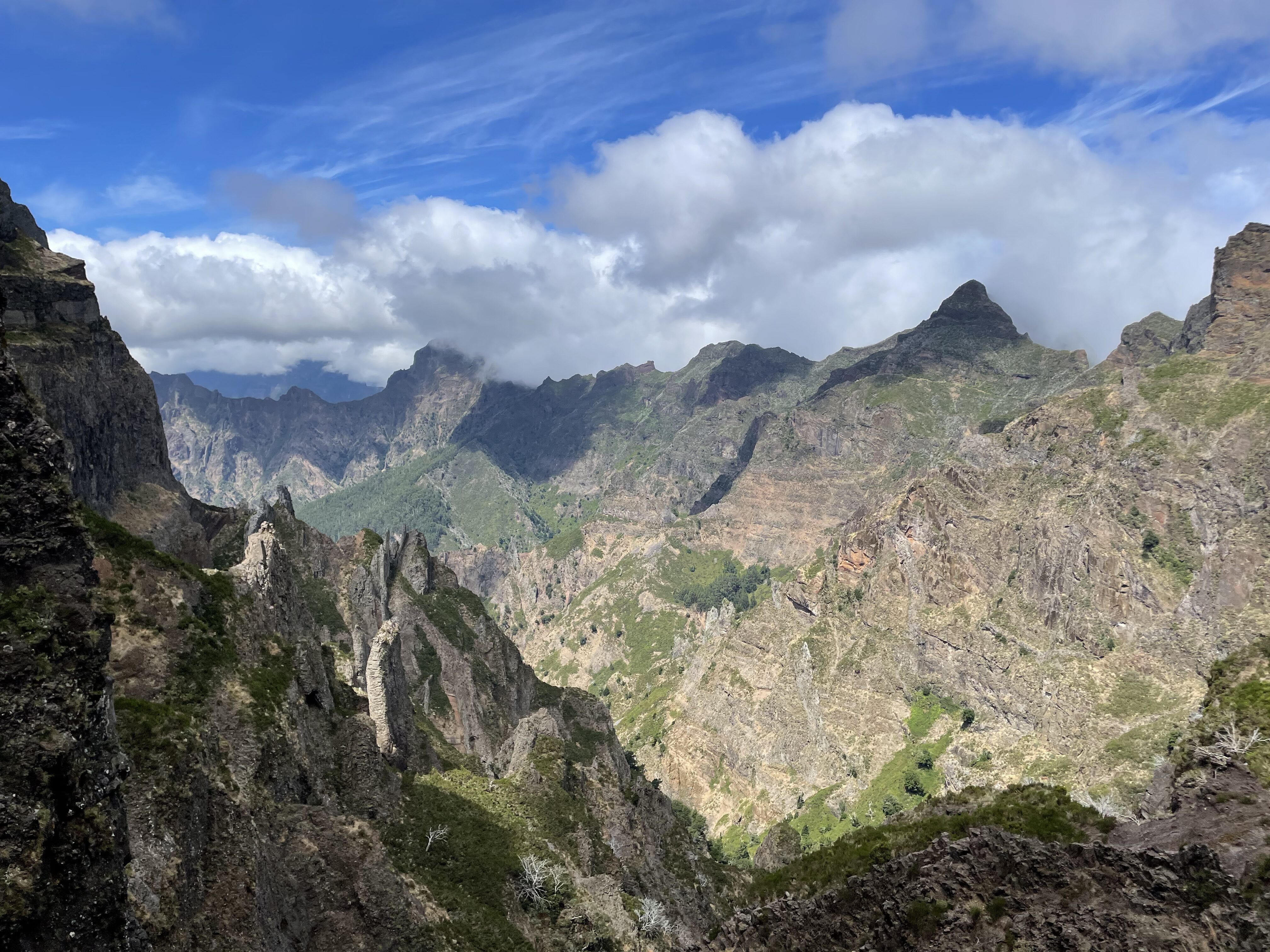 Beautiful, jagged mountains in Madeira beneath a cloudy blue sky.