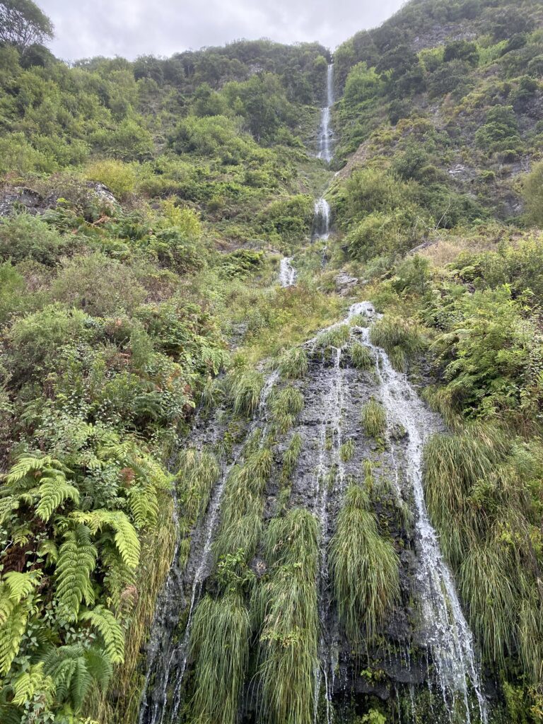 A waterfall flowing down a vibrant green mountain in Madeira.