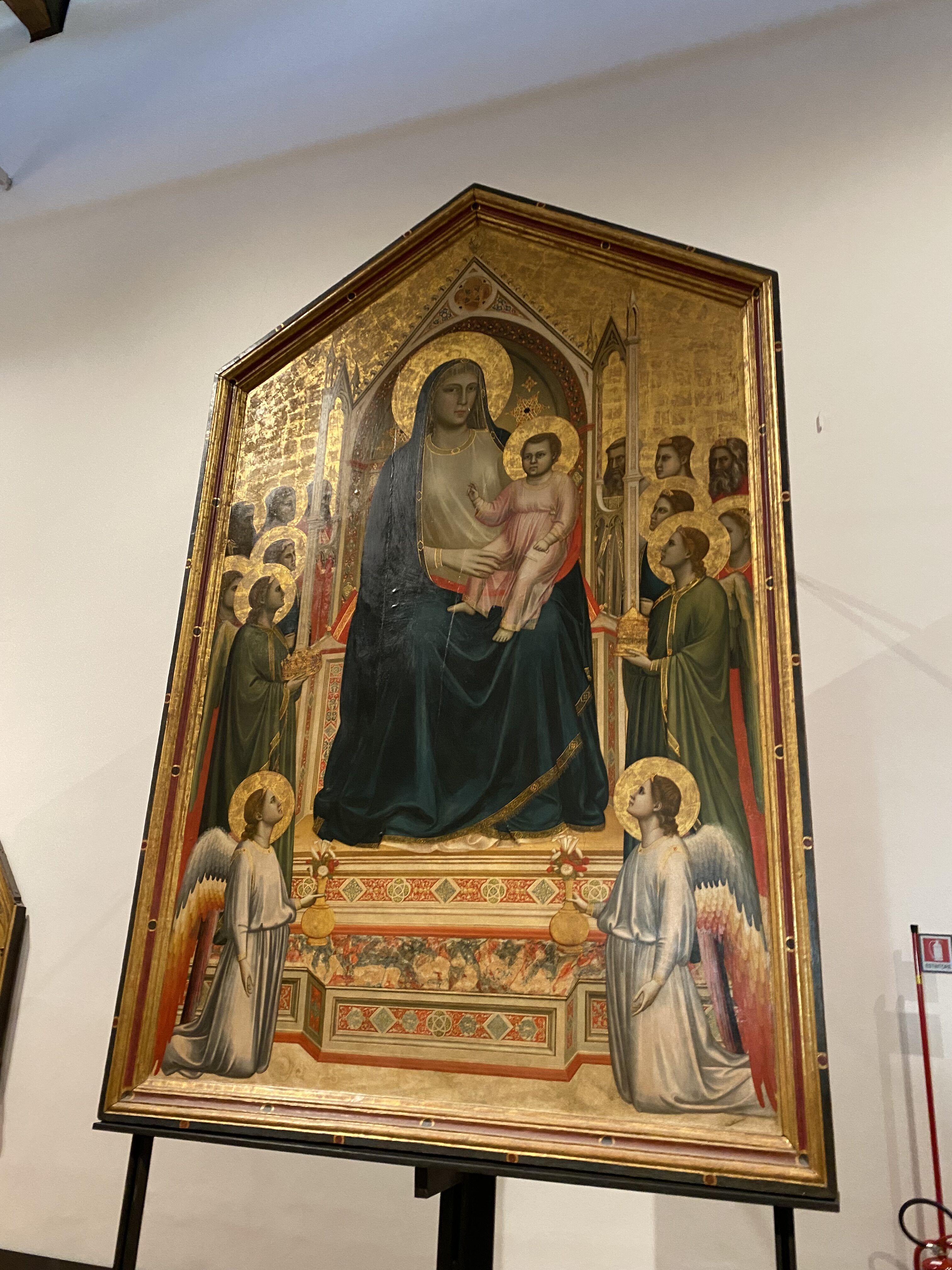 A decorated medieval altarpiece depicting the Virgin Mary holding baby Jesus surrounded by saints and angels.