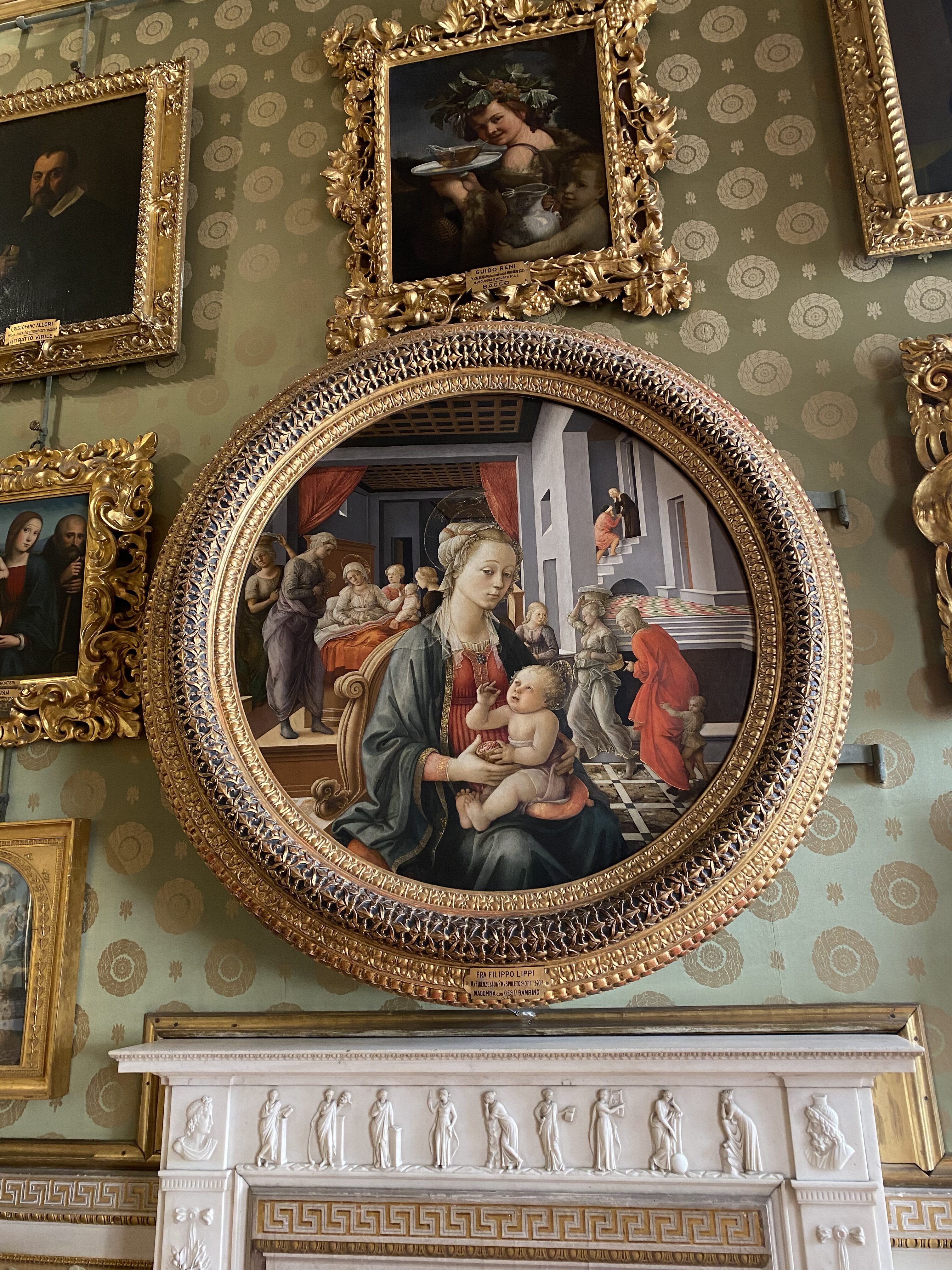 A round portrait of a mother holding a child in the Pitti Palace in Florence. Other paintings in gold frames surround the central round painting.