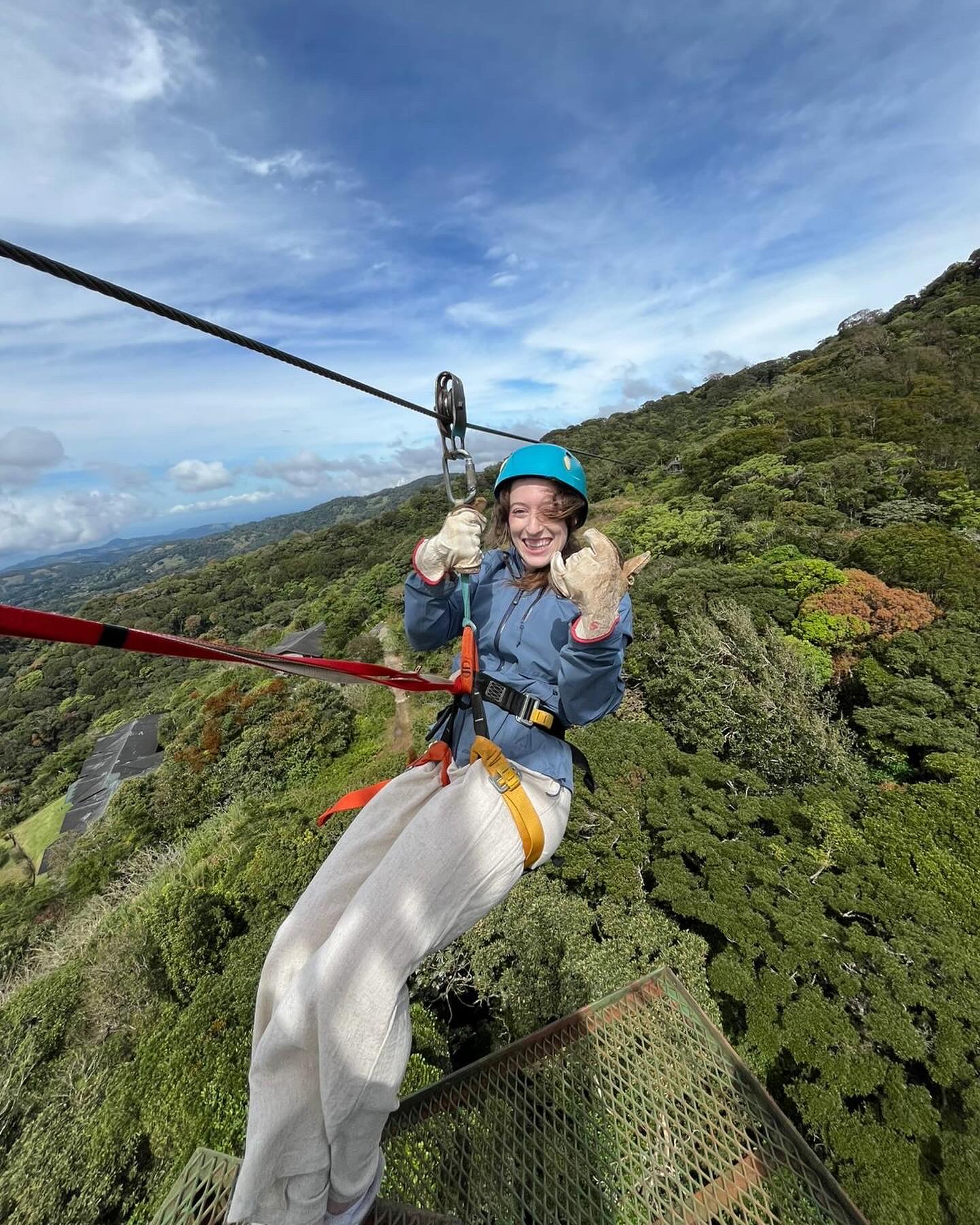 Bella zip-lining away holding up a "hang loose".
