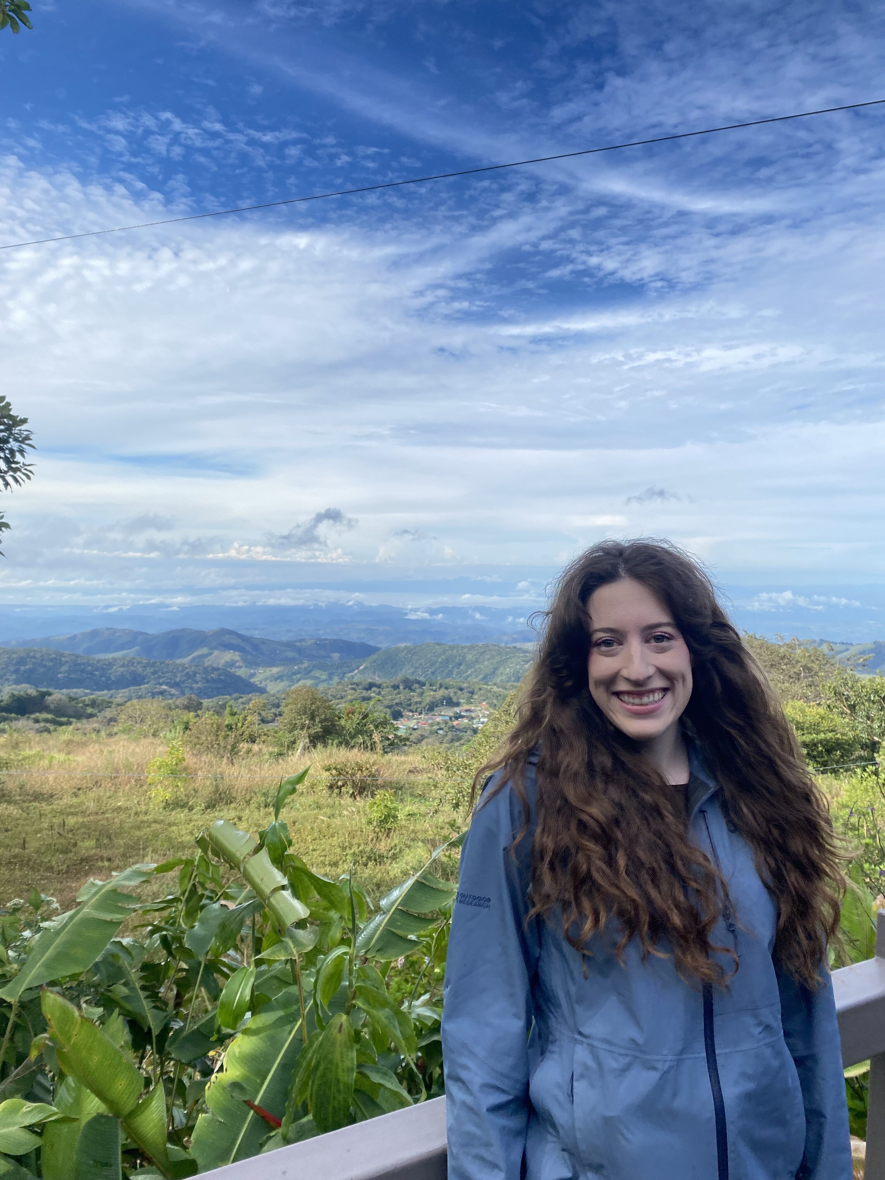 Bella smiling in front of the green hillsides of Monteverde.