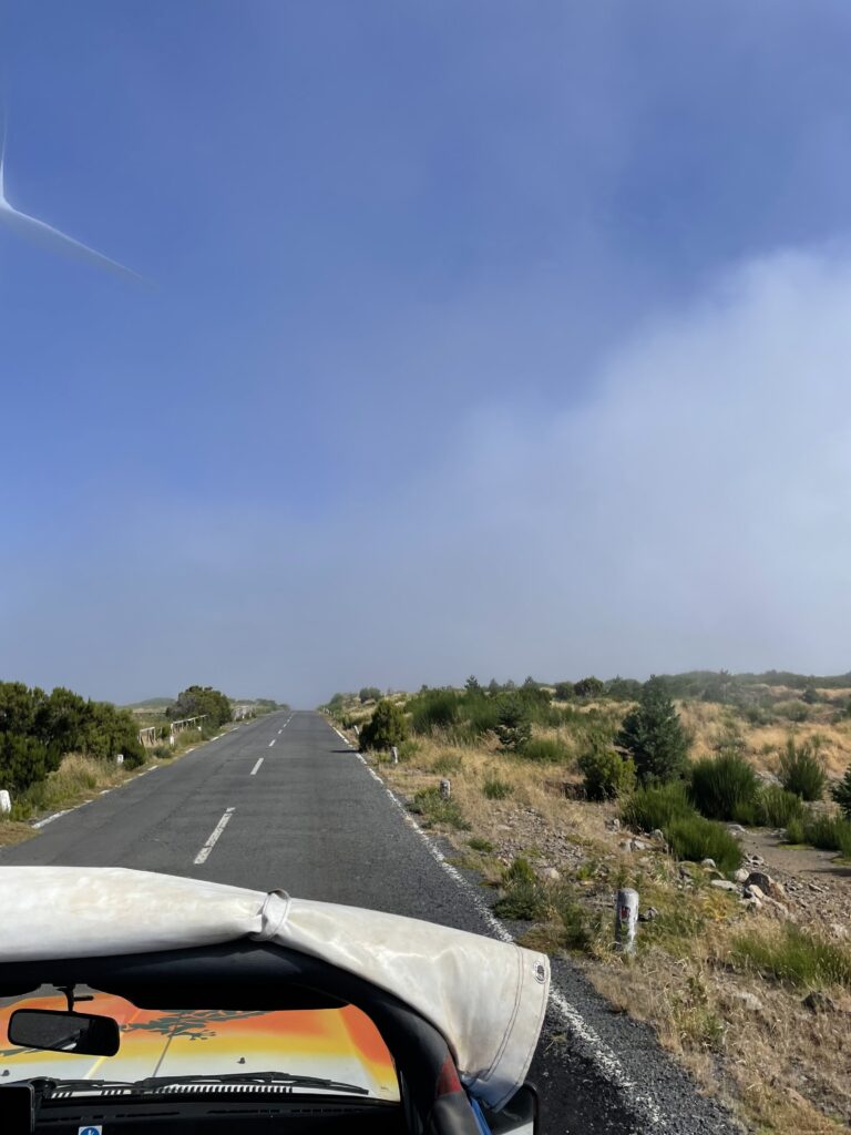 The top of a 4x4 vehicle with a view of the road. Mystical fog begins to form in the distance.