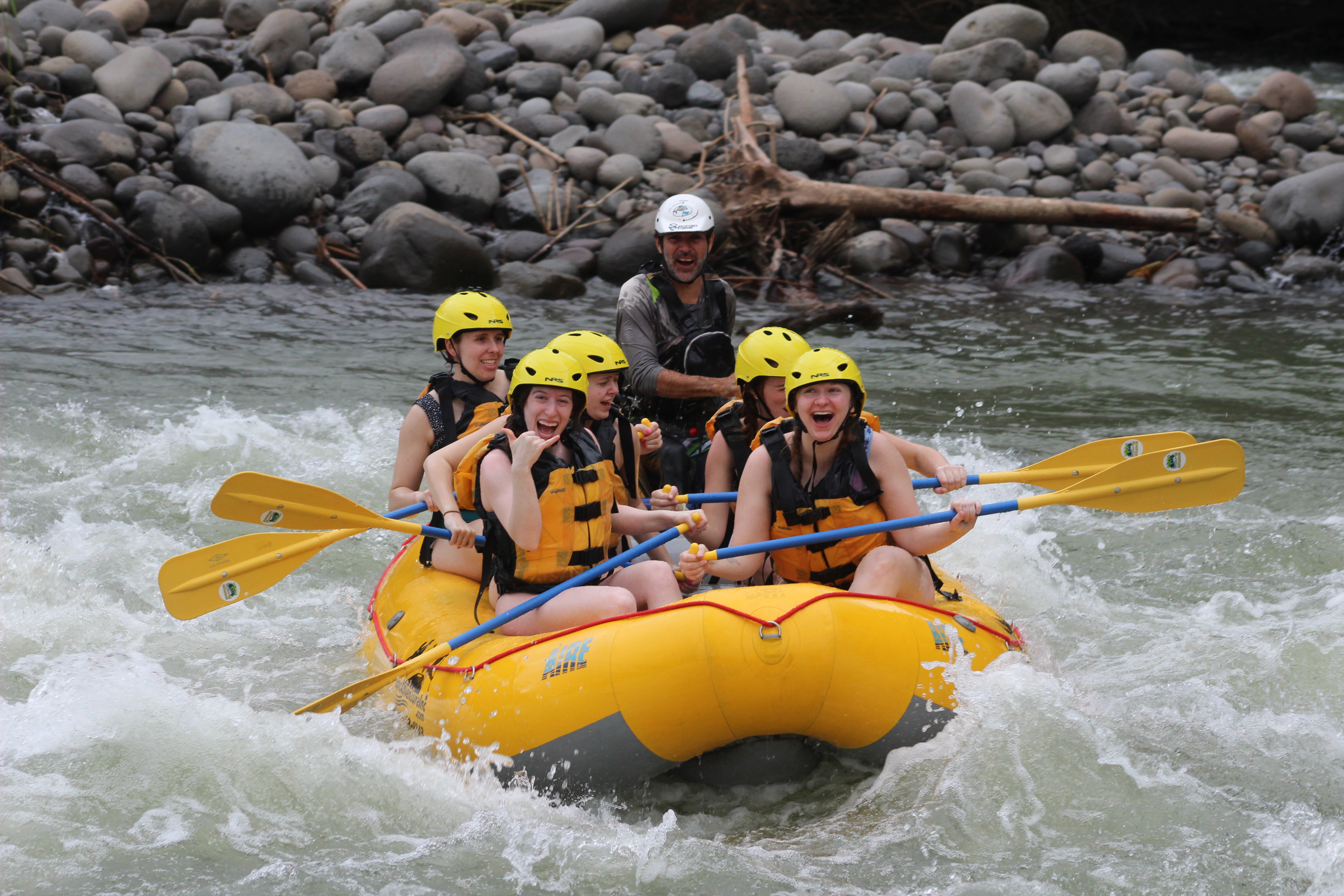 Bella holding up a "hang loose" sign while whitewater rafting the Sarapiqui River.
