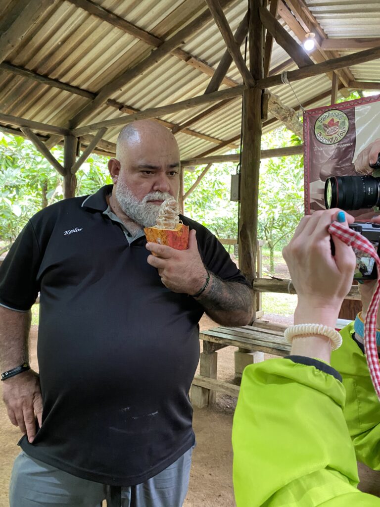 A tour guide holding a cacao fruit up for the camera.