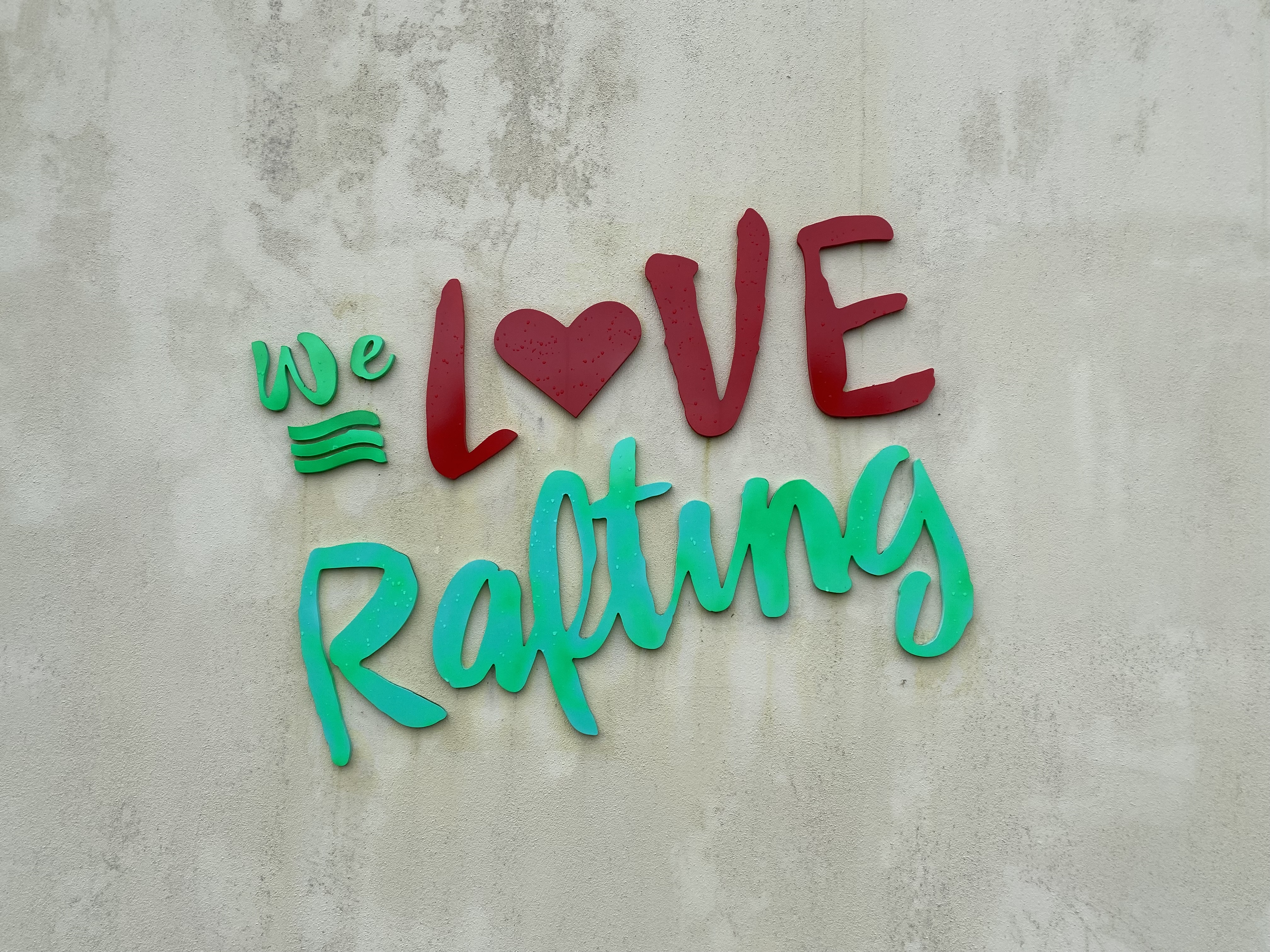 A sign on a concrete wall that says, "We Love Rafting".
