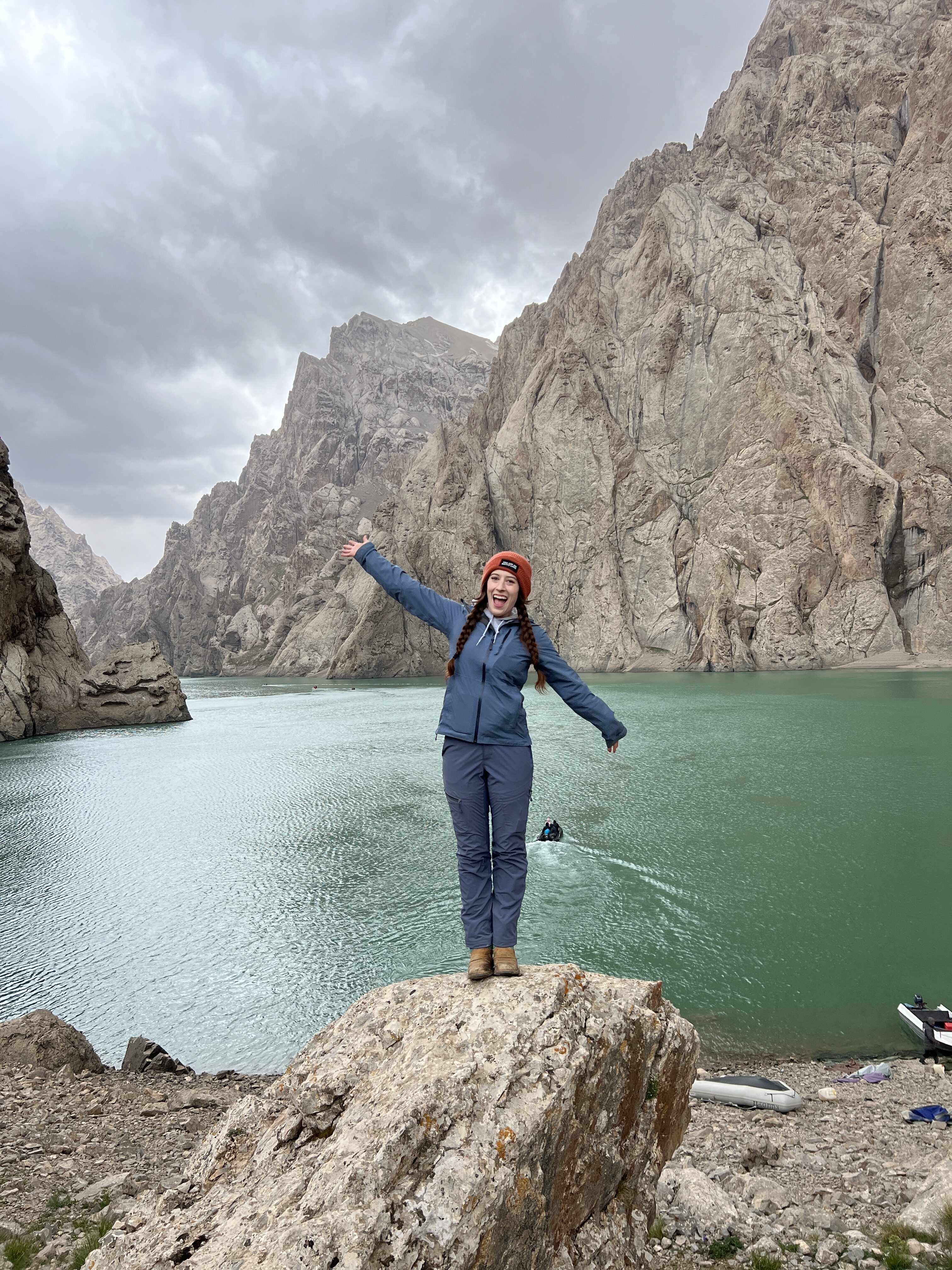 Bella posing on a rock with her arms out, in front of Kel Suu lake.