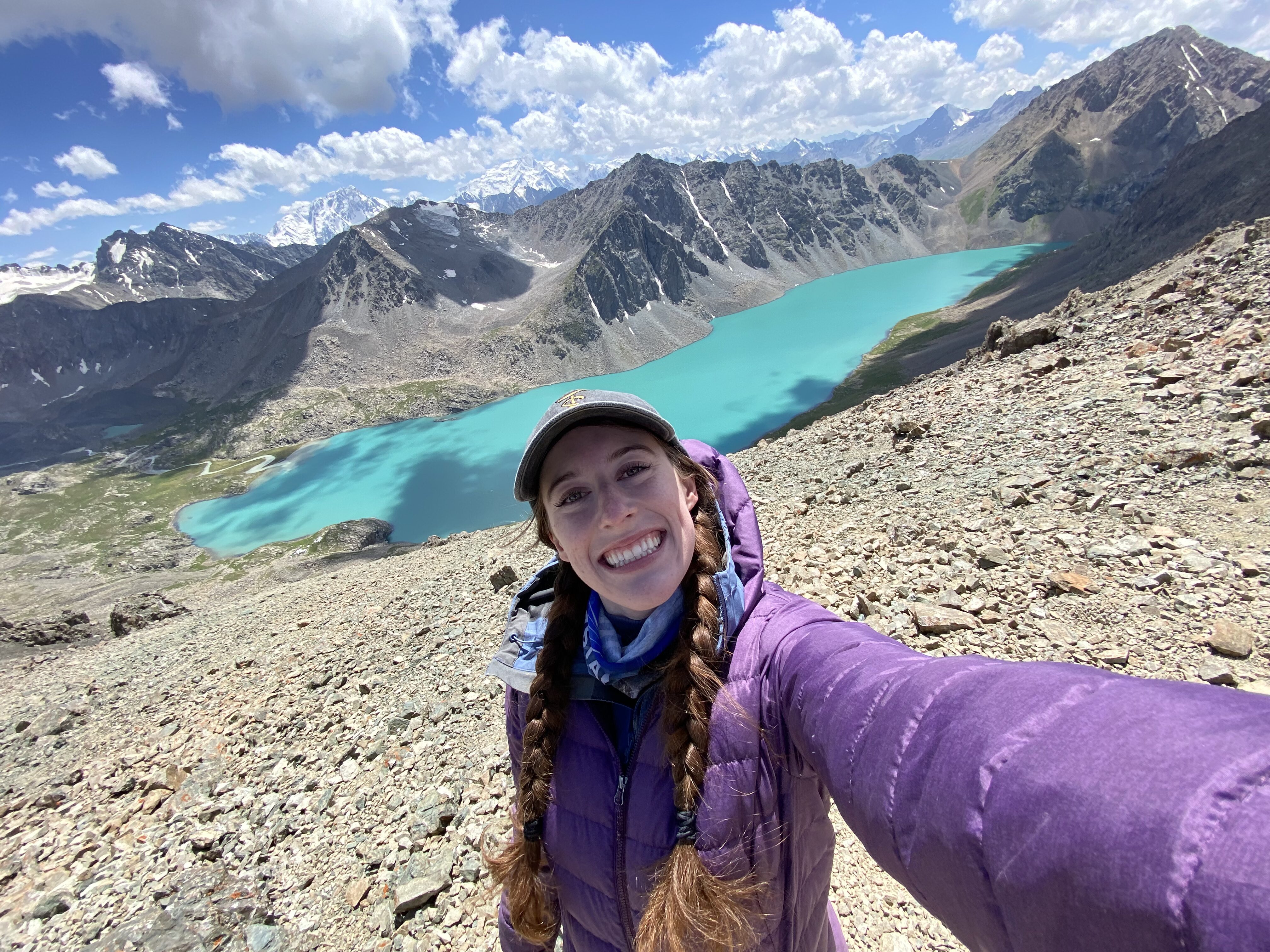 Bella taking a selfie at the top of Ala Kul pass, with the lake shimmering below.