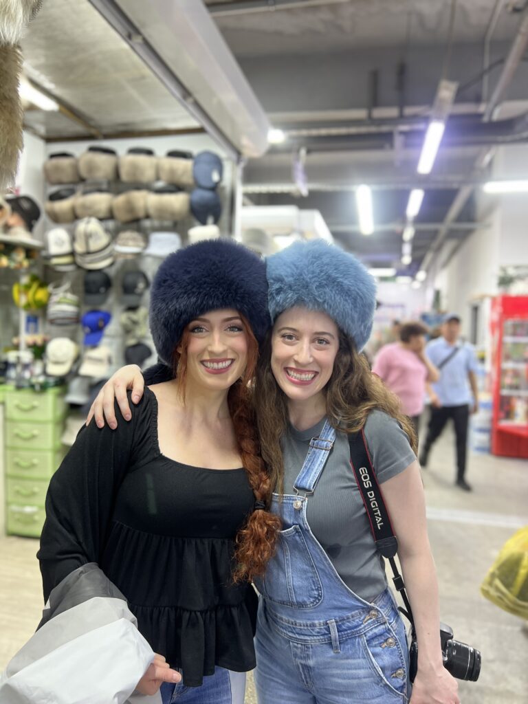 Lily and Bella wearing glamorous blue Kyrgyz faux fur hats.