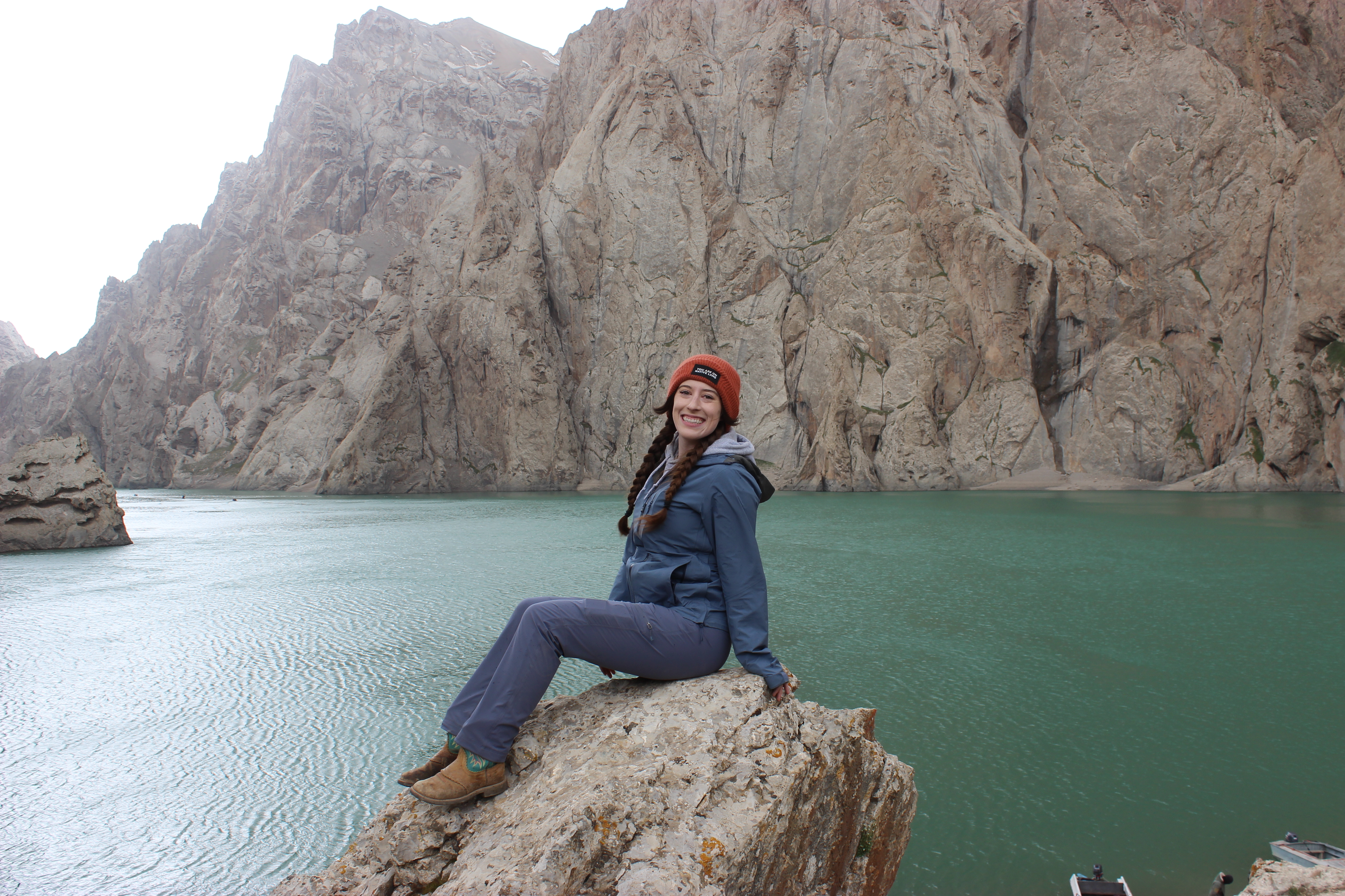 Bella sitting on a rock in front of Kel Suu lake.