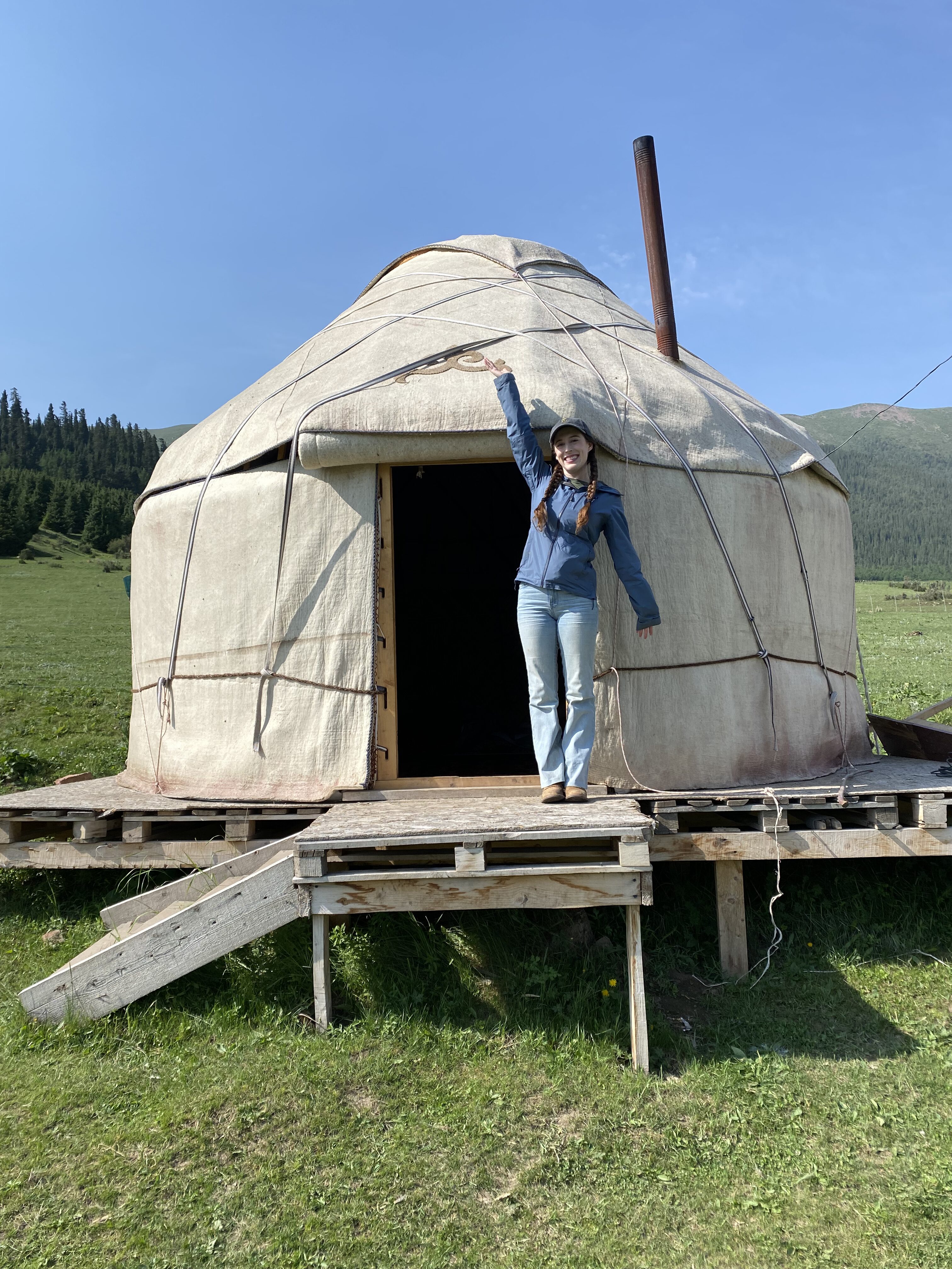 Bella standing in front of a yurt.