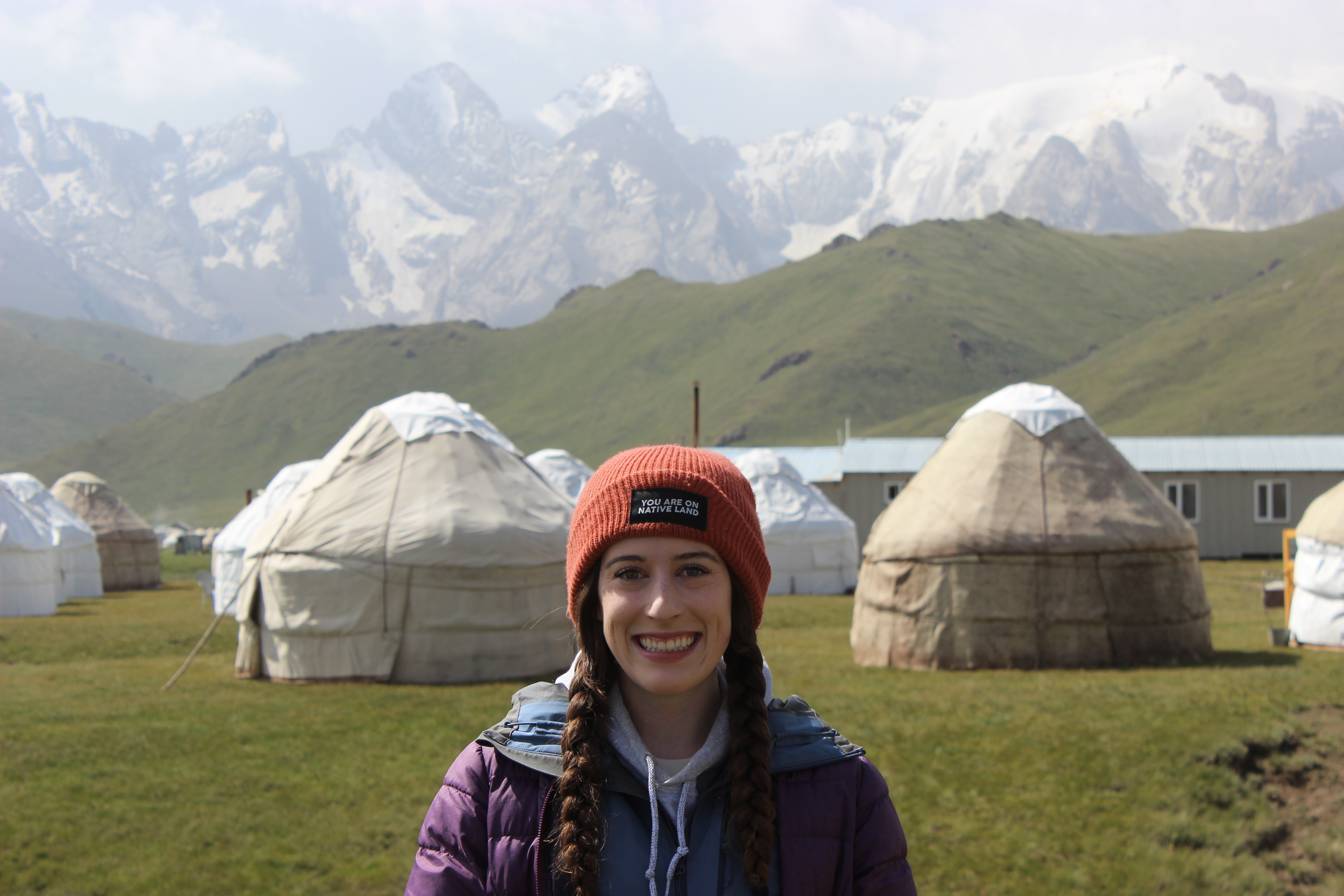Portrait of Bella in front of a local yurt camp in the Kok Kiya valley, with the mountains peeking through in the background.