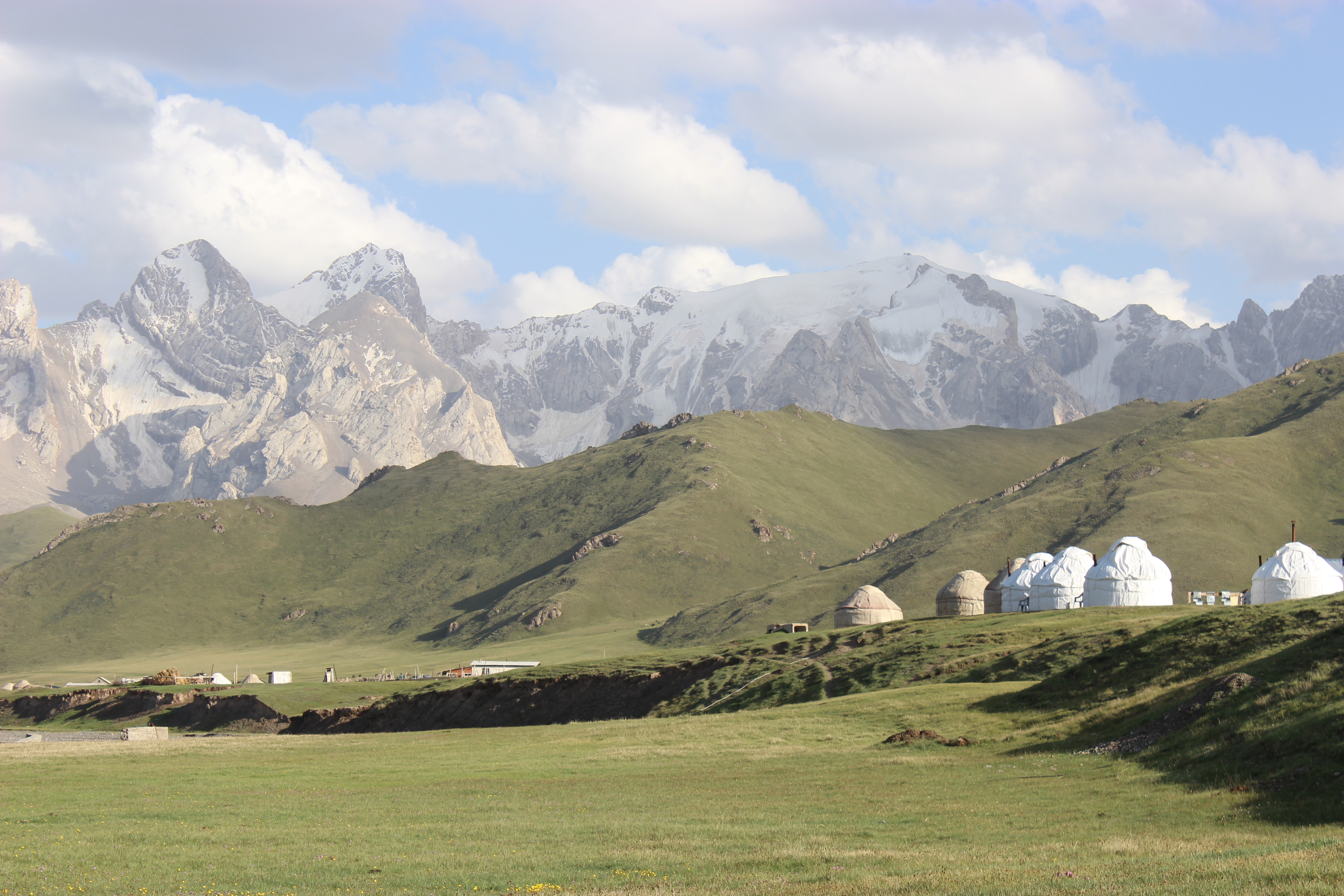 The beautiful Kok Kiya valley with a yurt camp and jagged peaks above the grassy plains.