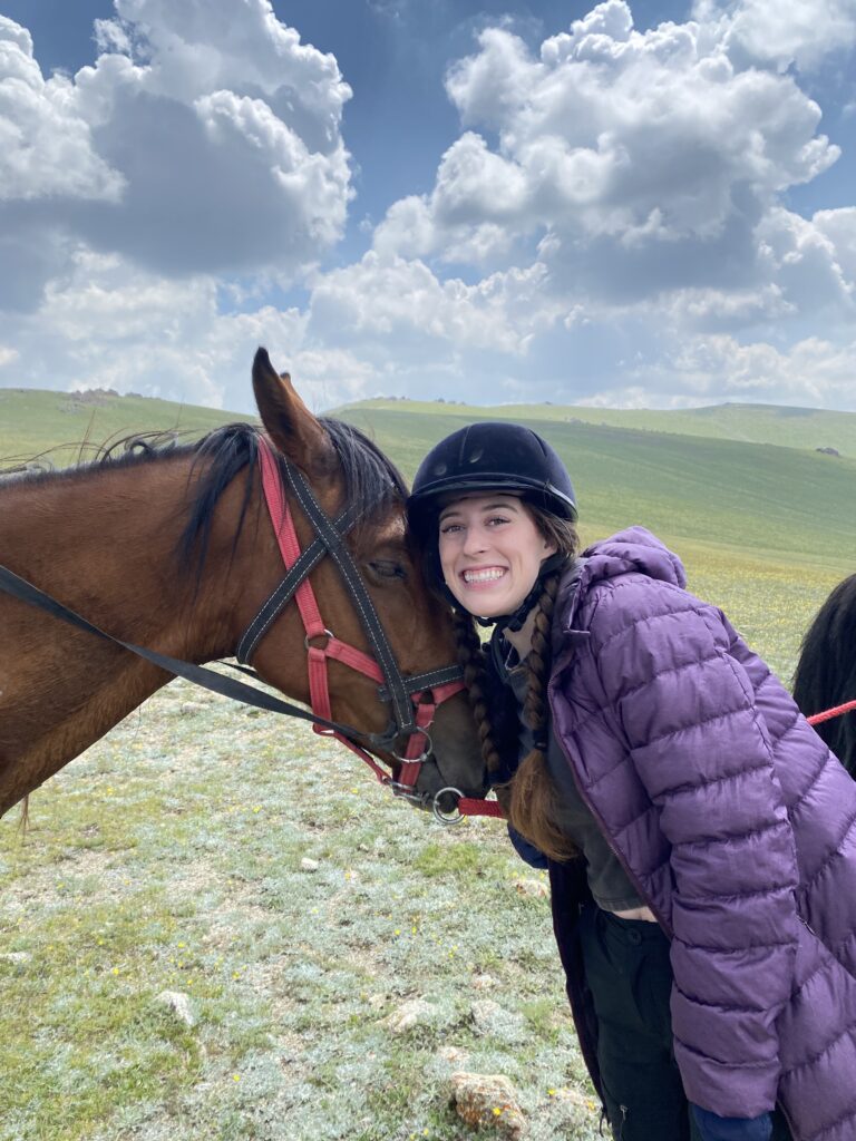 Bella poses in her bright purple jacket with her chestnut colored horse, Chitoro.