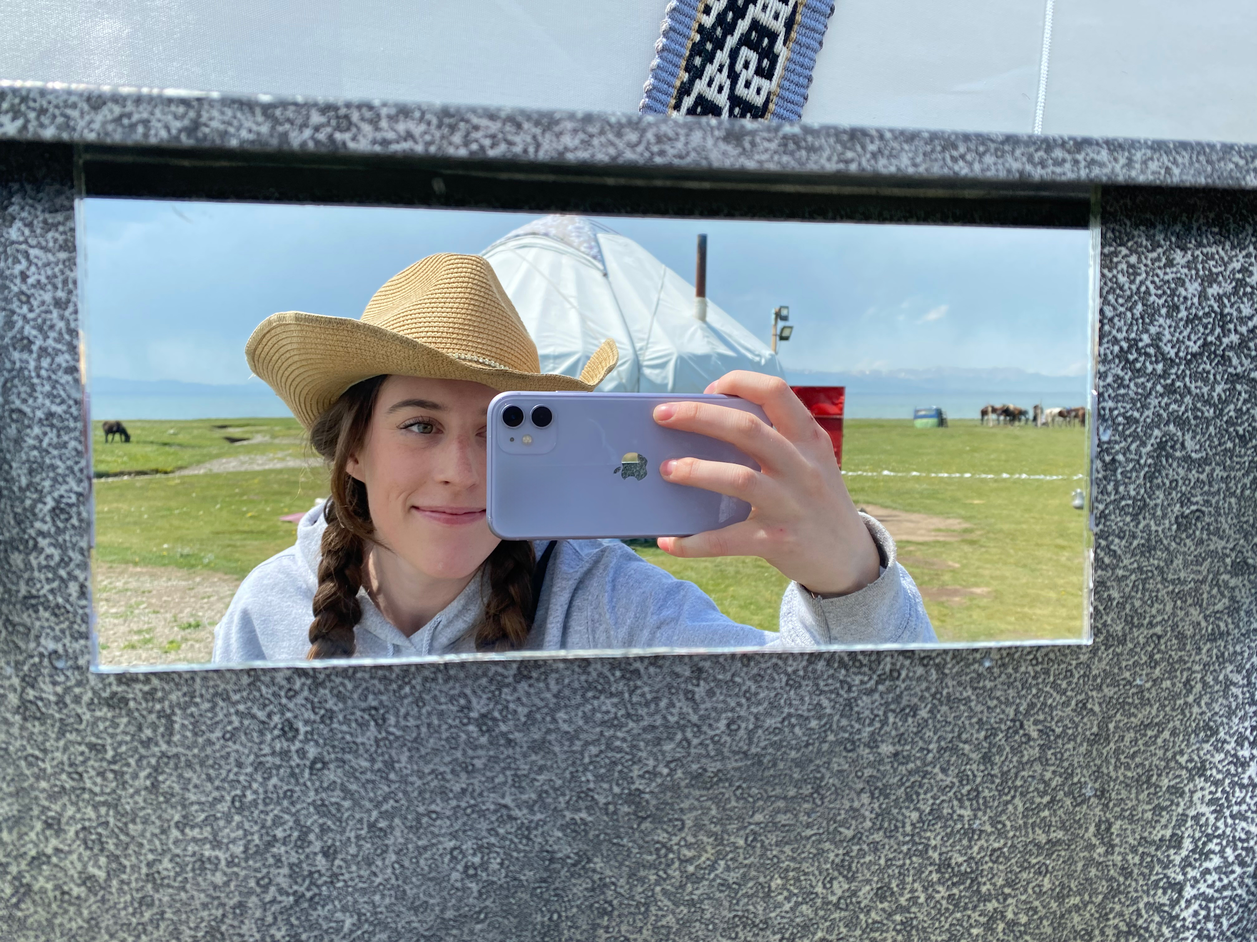 Bella holds her purple iPhone up to the mirror for a picturesque selfie with a yurt in the background.