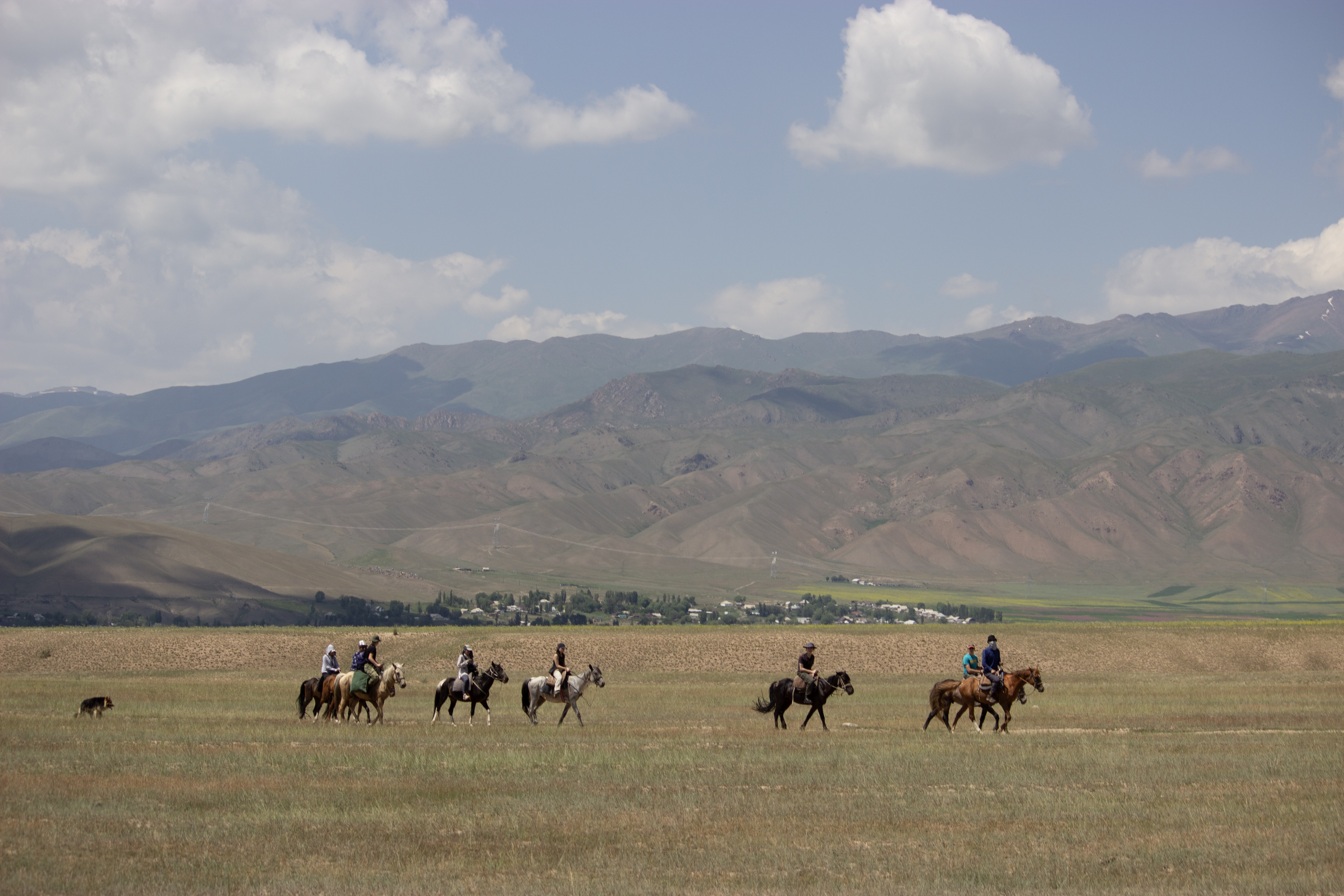 A group of horseback riders riding through a valley just outside of Kyzart village in Kyrgyzstan.