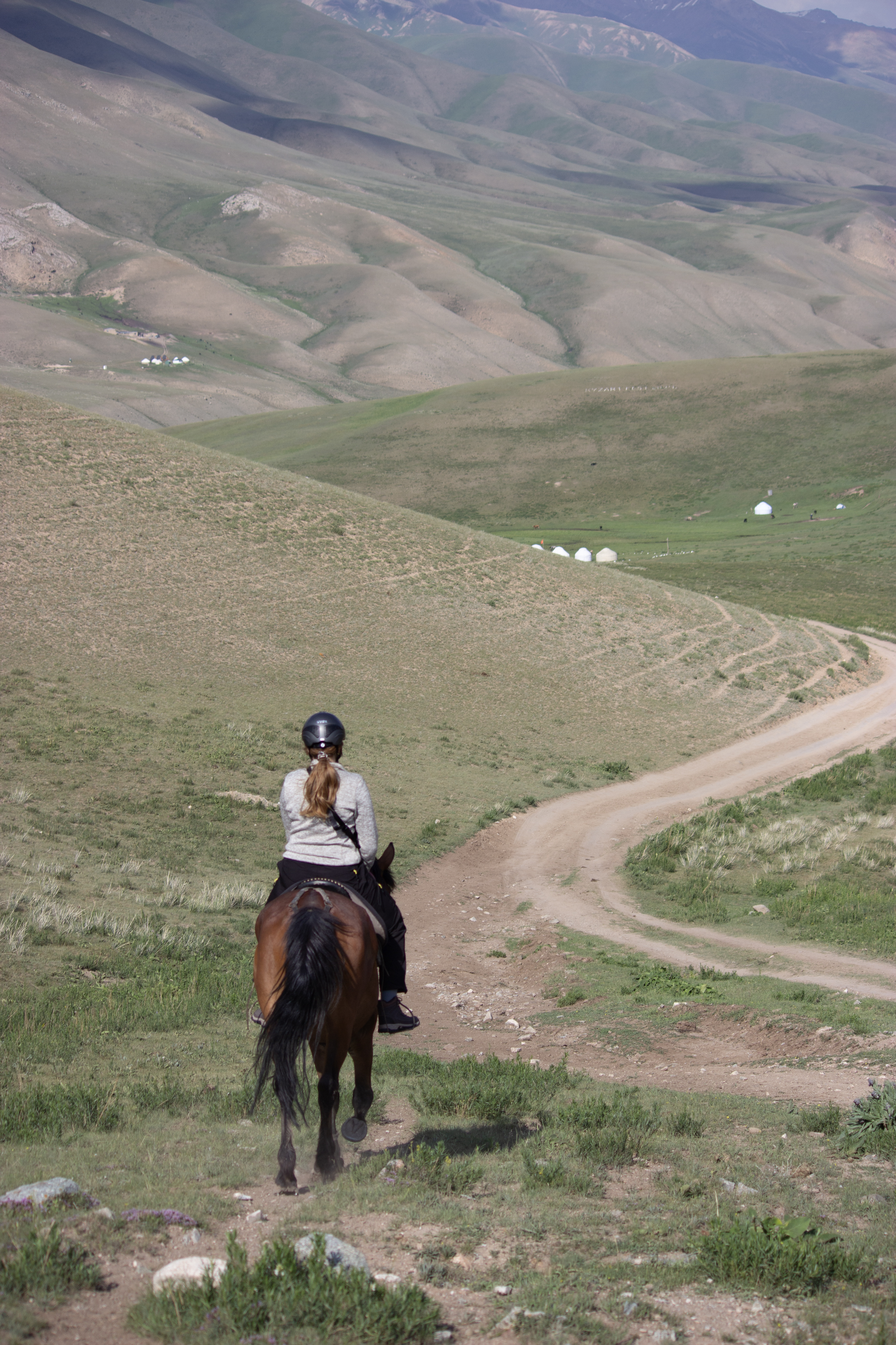 A young horseback rider riding towards a remote yurt camp in Kyrgyzstan.