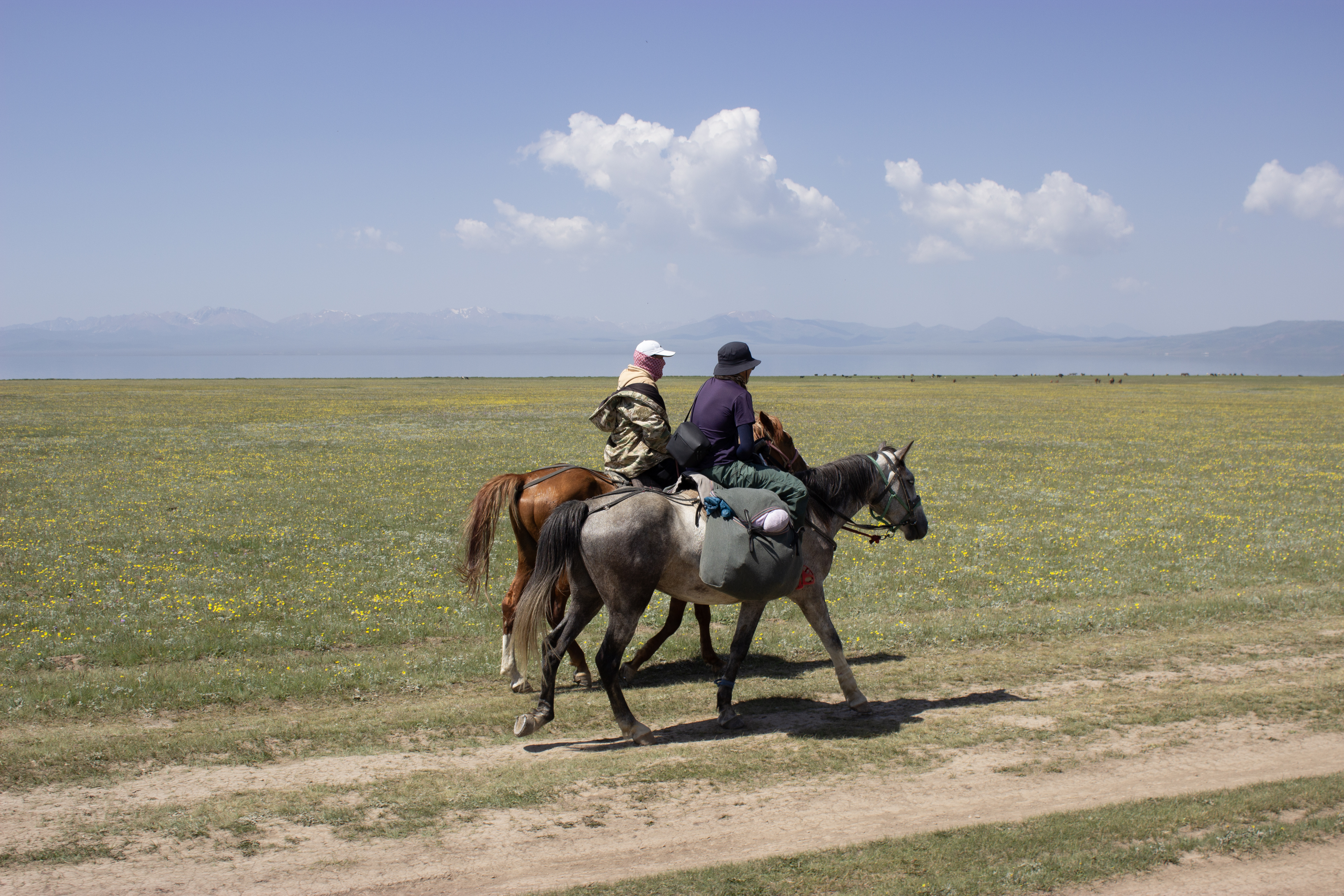 A pair of local Kyrgyz guides riding side-by-side near Song Kul lake.