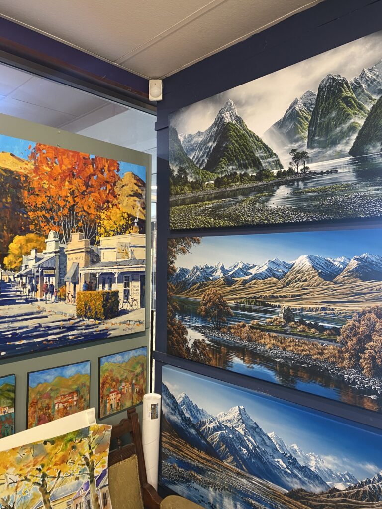 A local art gallery in Queenstown showcasing landscapes of New Zealand including Milford Sound and scenic snow-capped mountain ranges.