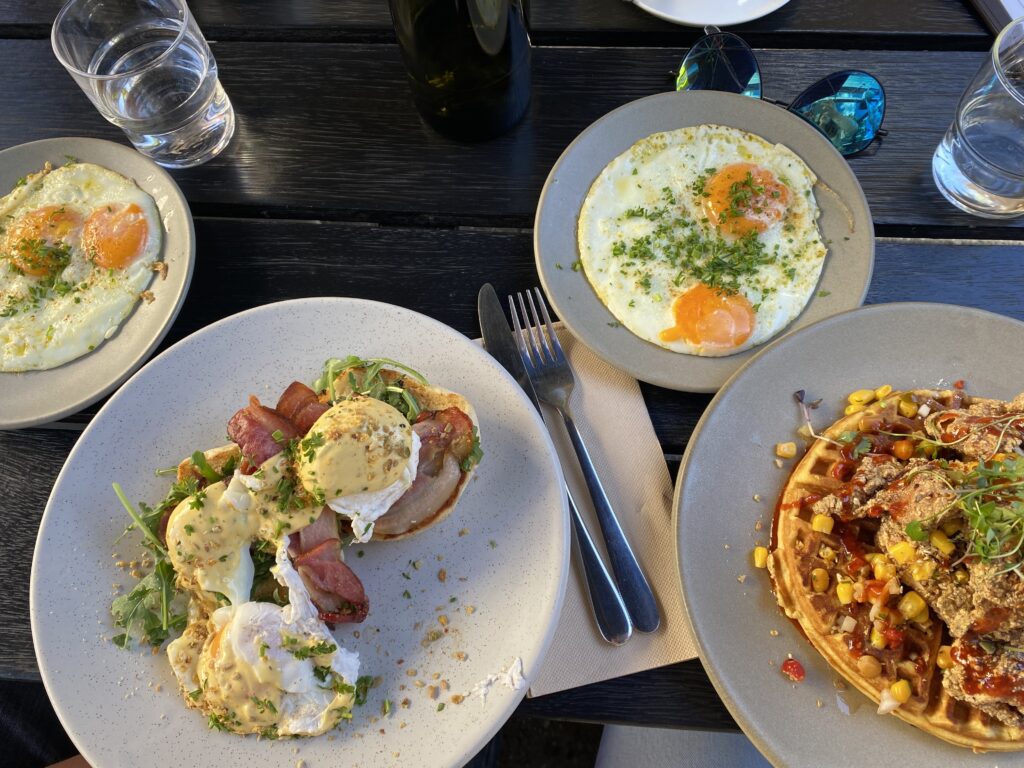 A delicious spread of breakfast food from Odd Saint (Queenstown), including Eggs Benedict and Chicken and Waffles.