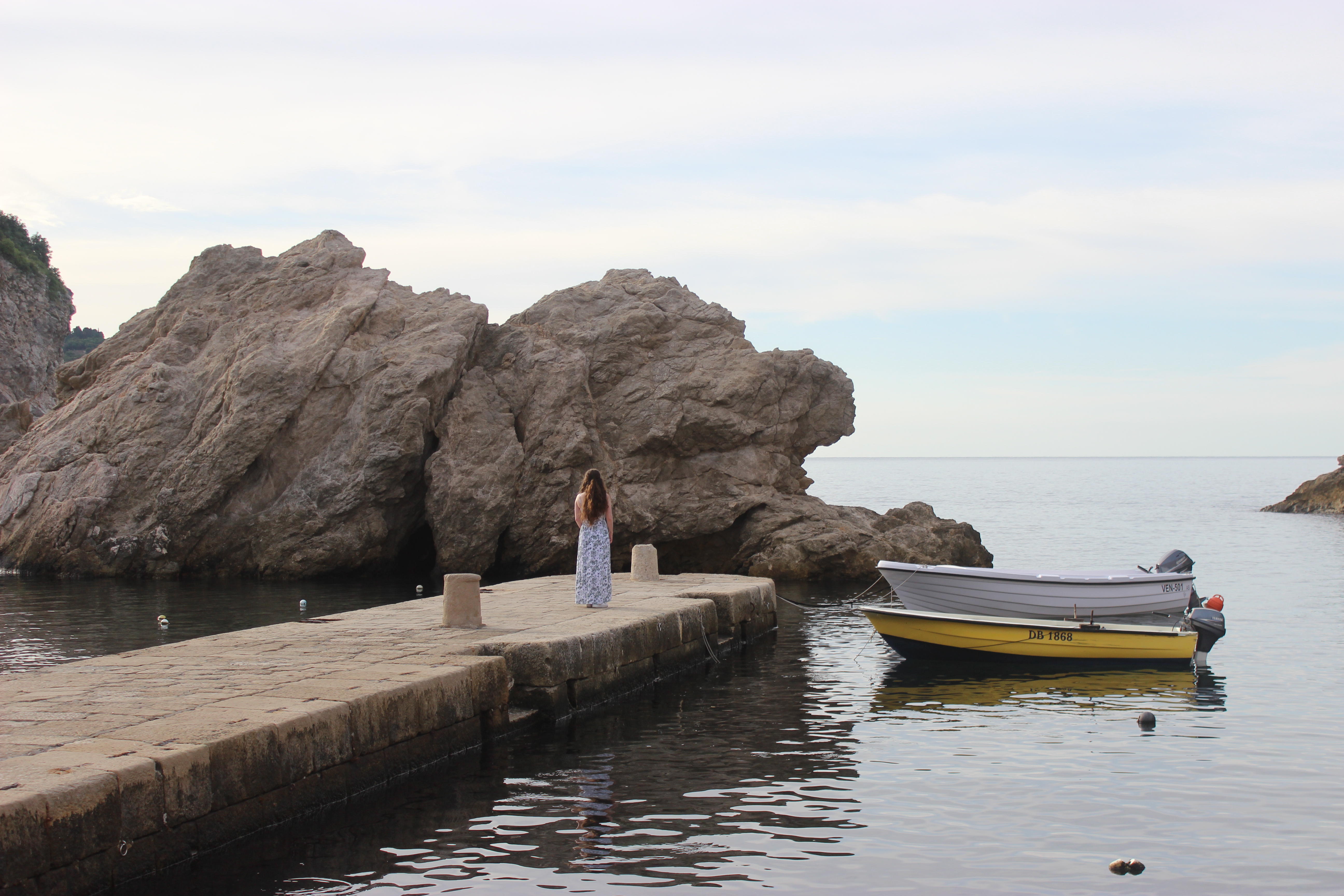 A scenic boat dock in Dubrovnik witha rock in the bay.