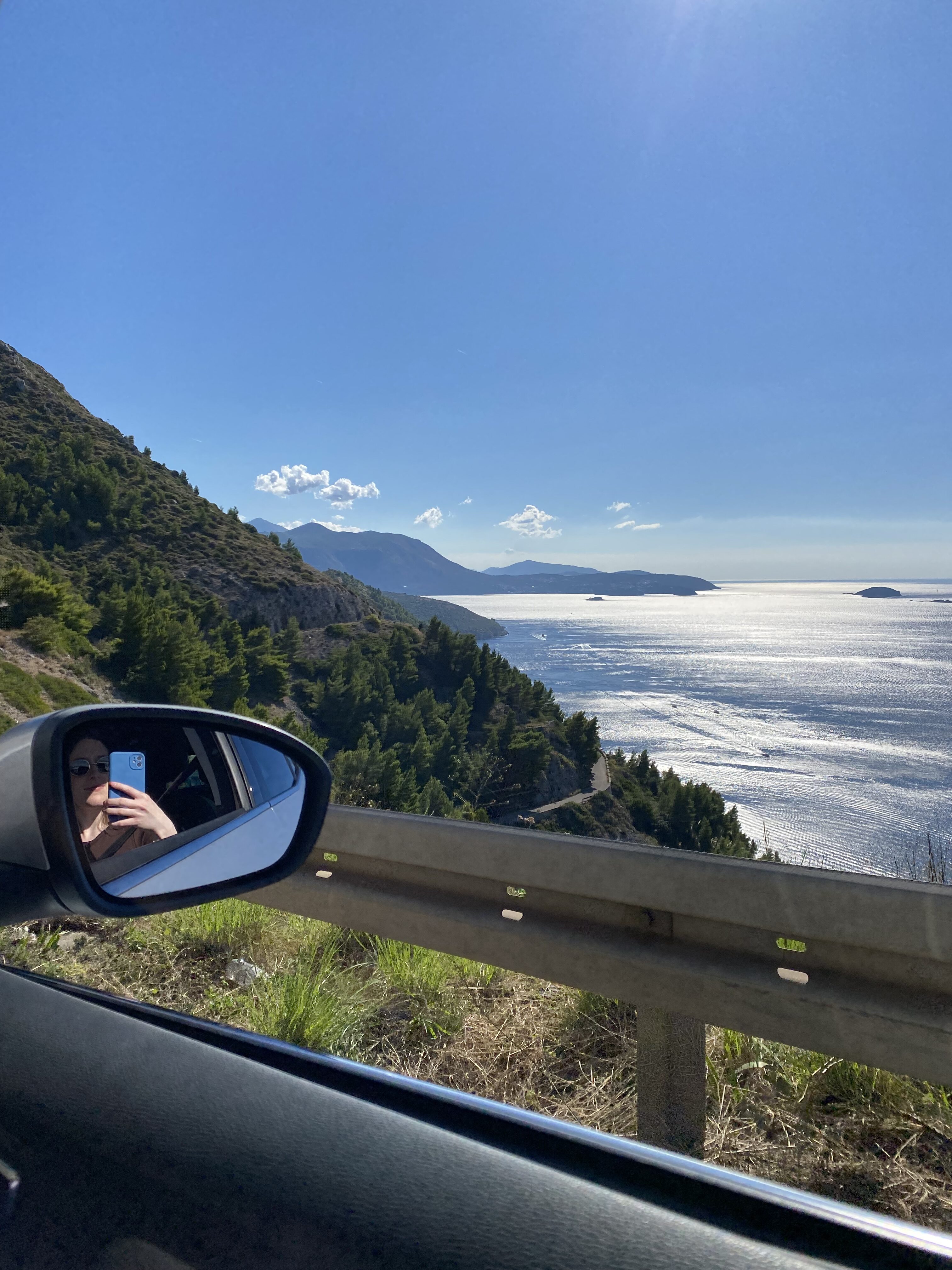 The passenger mirror of a car with a scenic view of the Adriatic Sea.